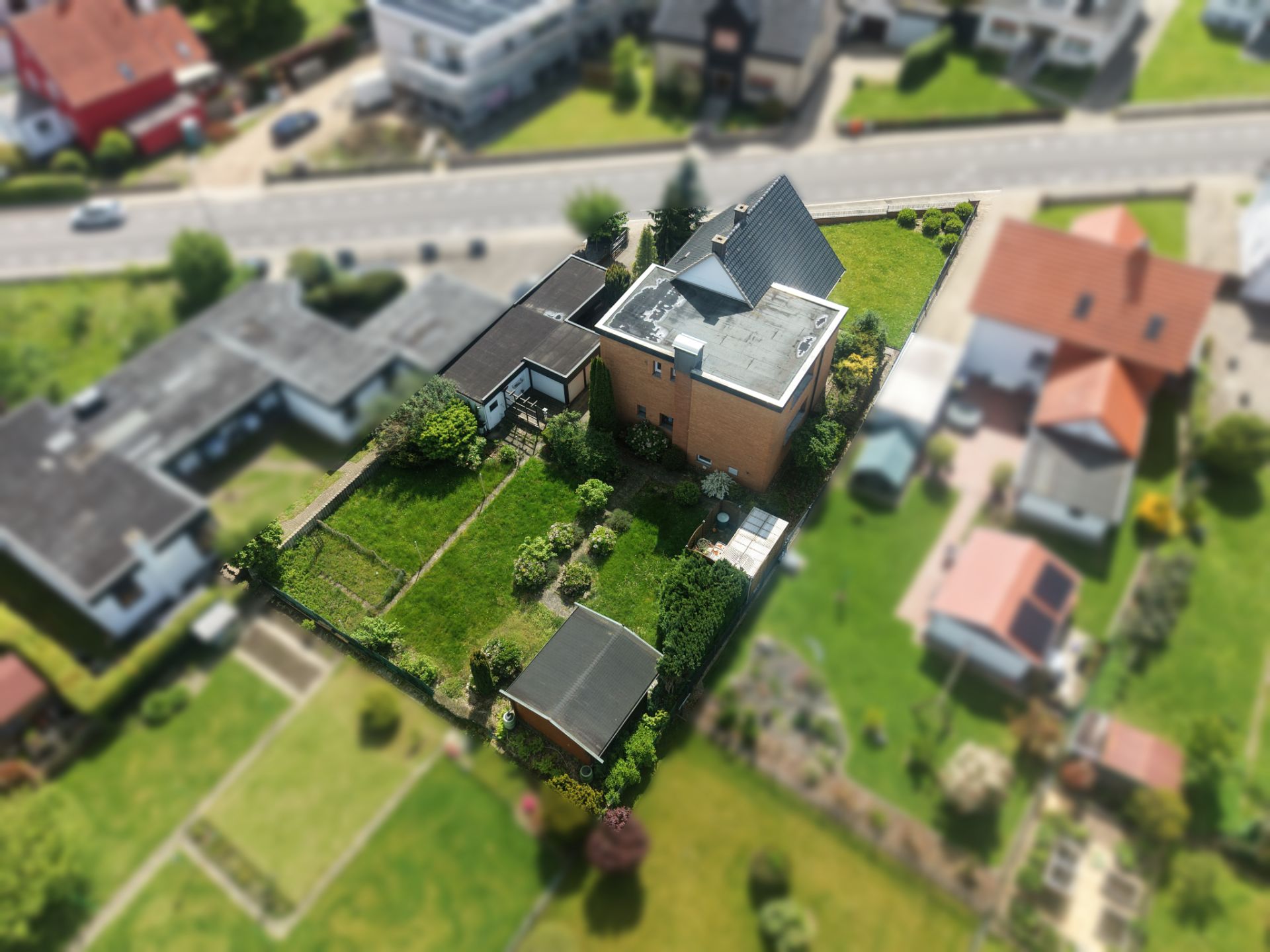 Luftaufnahme eines Wohnhauses mit Garten und Nebengebäude in einer Wohngegend.