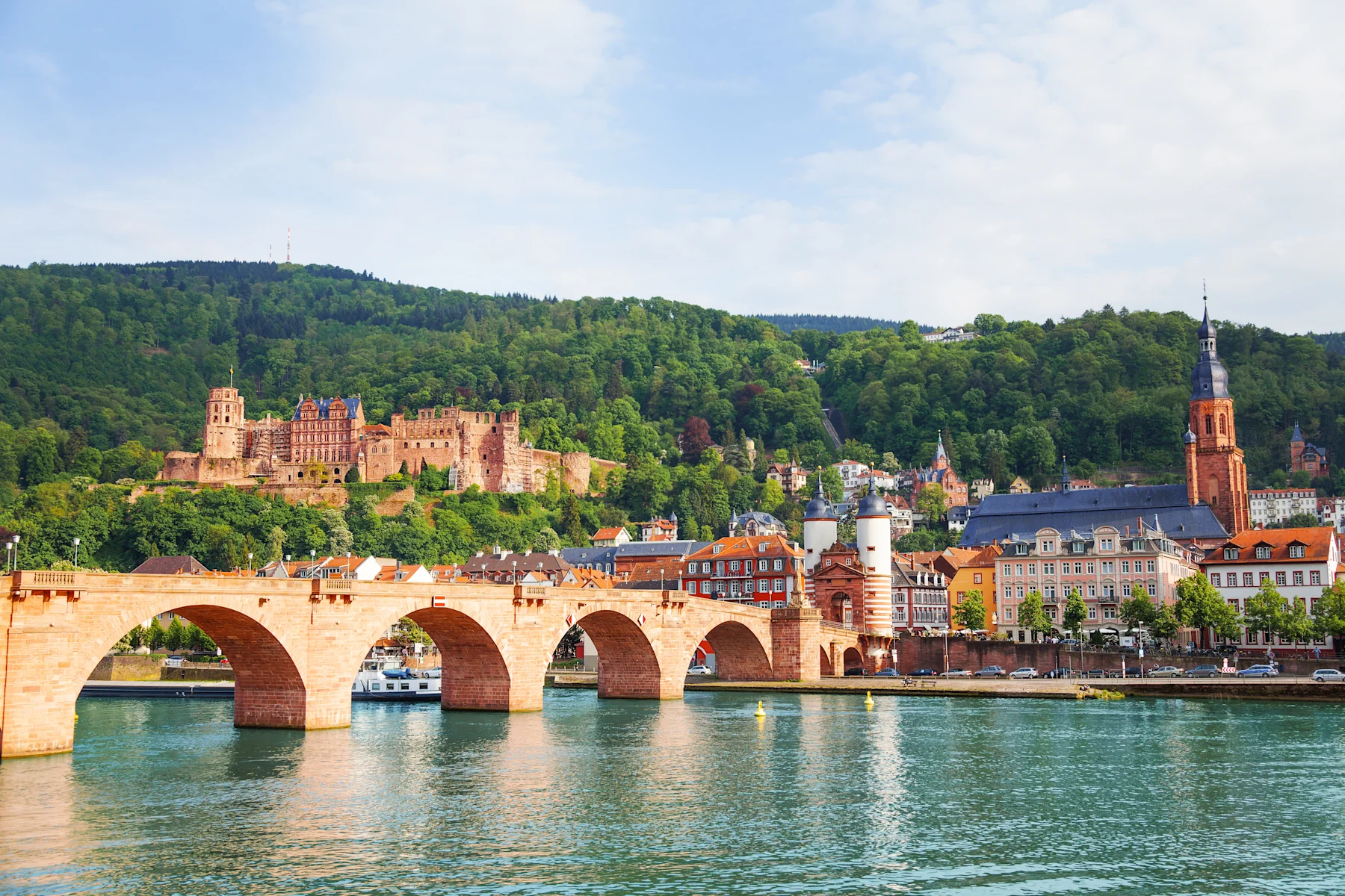 Steinerne Brücke über einen Fluss mit Schloss und Altstadthäusern im Hintergrund.