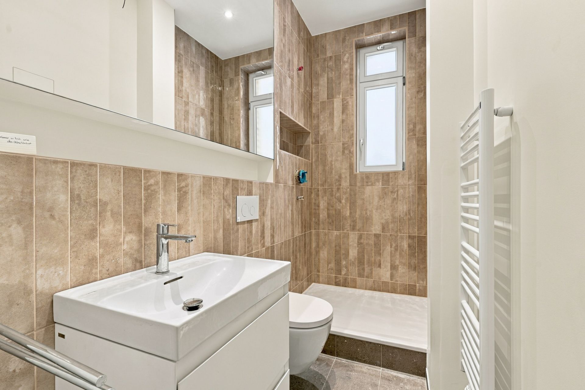 Modernes Badezimmer mit Waschbecken, Spiegel, Toilette, Dusche und zwei Fenstern.