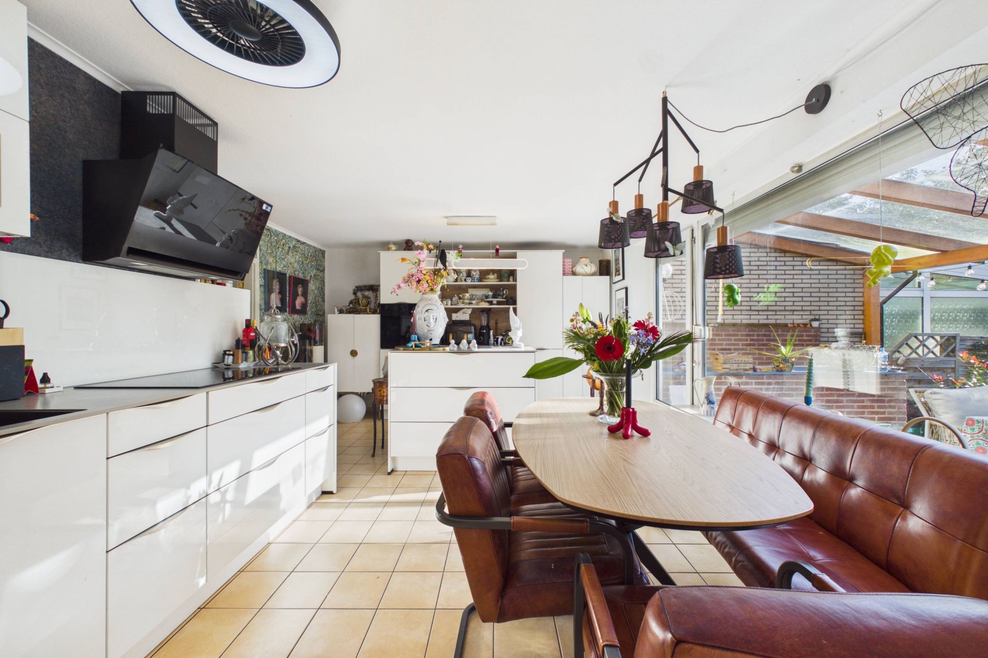 Moderne Wohnküche mit Esstisch, brauner Sitzbank und großen Fenstern zu einer Terrasse.