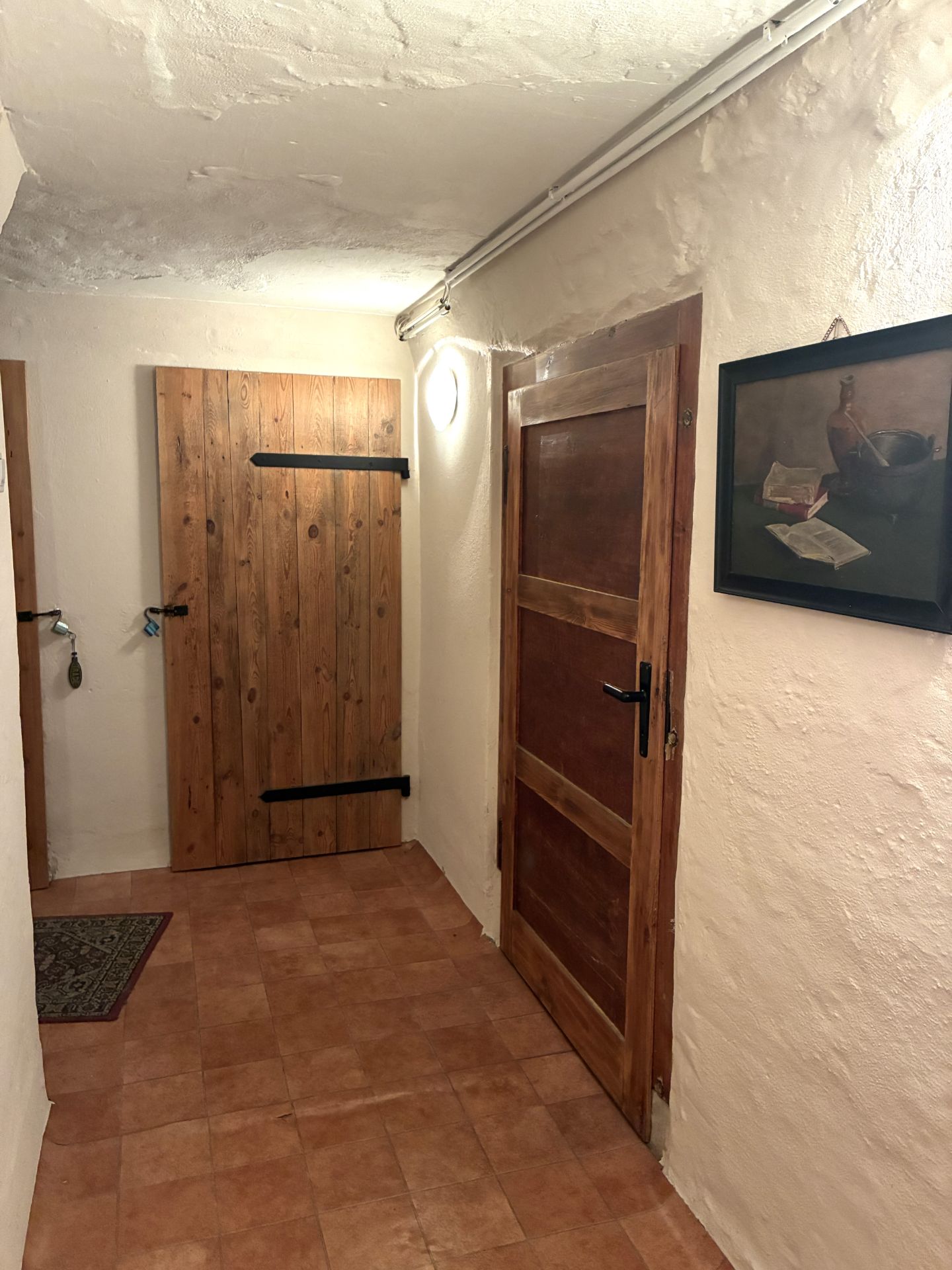 Flur mit zwei Holztüren, Keramikfliesenboden und einem Bild an der Wand.