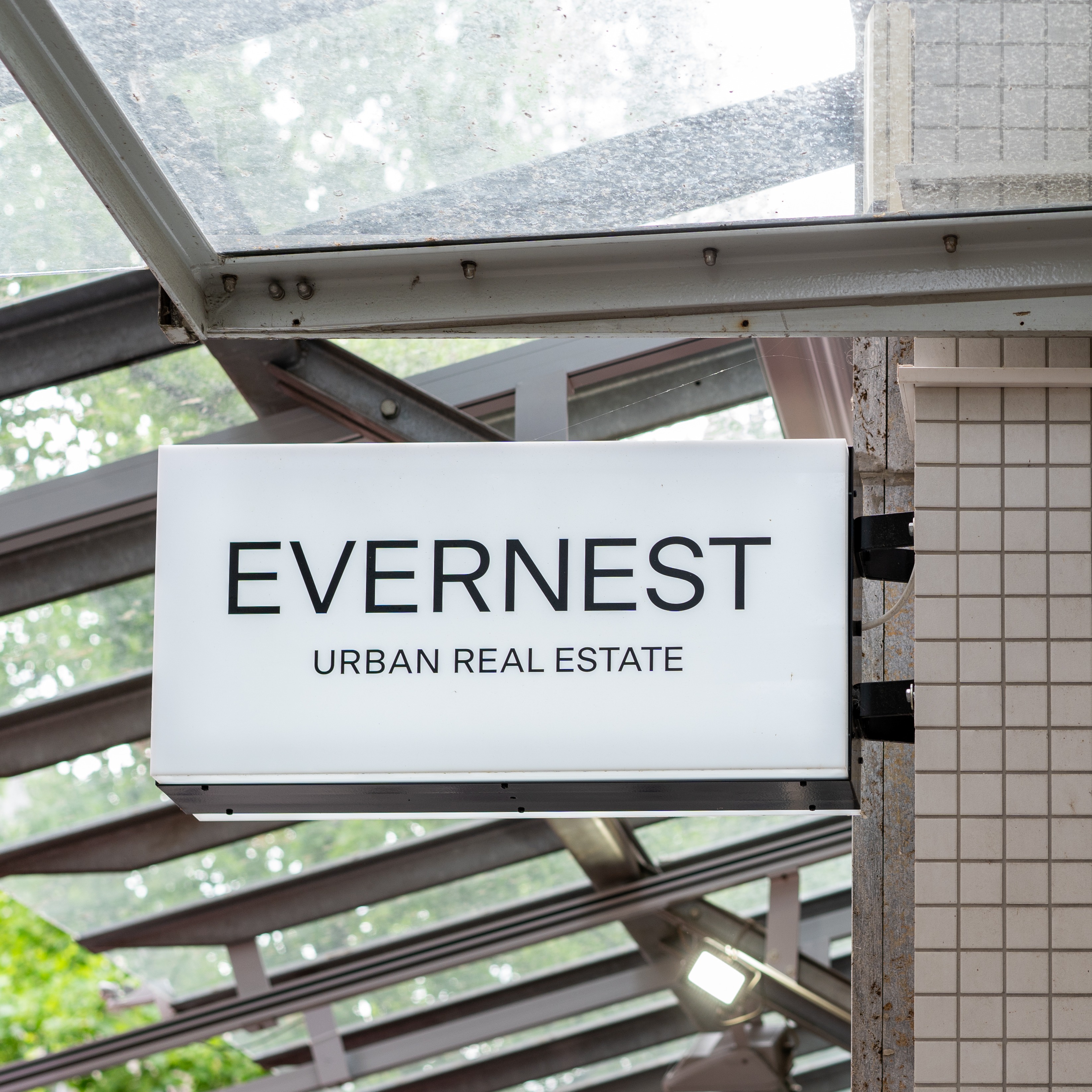 Leuchtreklame mit der Aufschrift 'EVERNEST URBAN REAL ESTATE' an einer Hauswand.