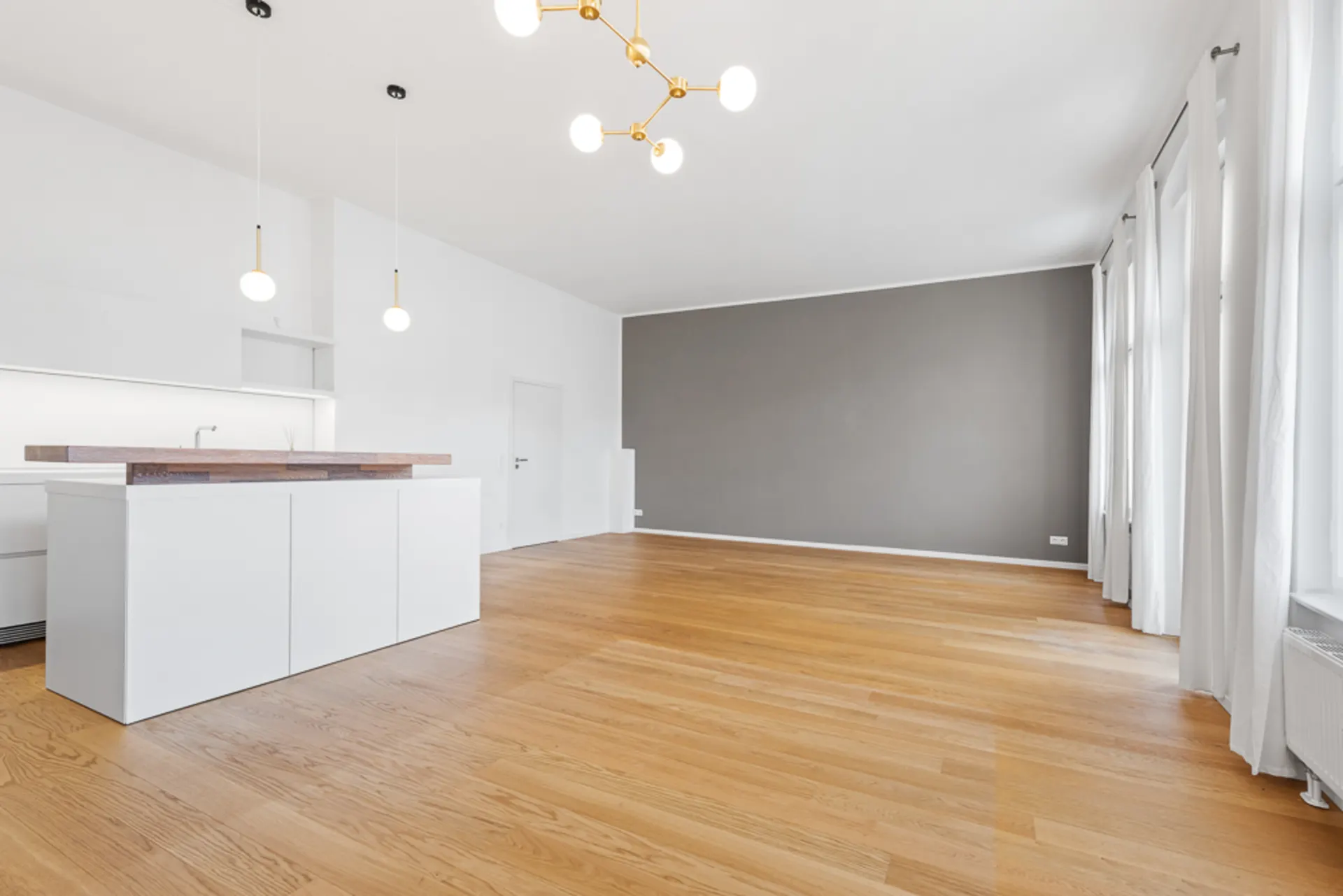 Helles Wohnzimmer mit Holzfußboden, offenen Fenstern, Küche und moderner Beleuchtung.