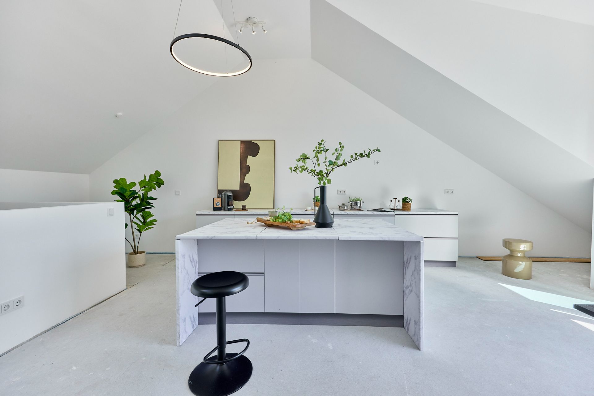 Moderne offene Küche mit Kücheninsel, Hocker, Pflanze und dekorativem Bild an der Wand.