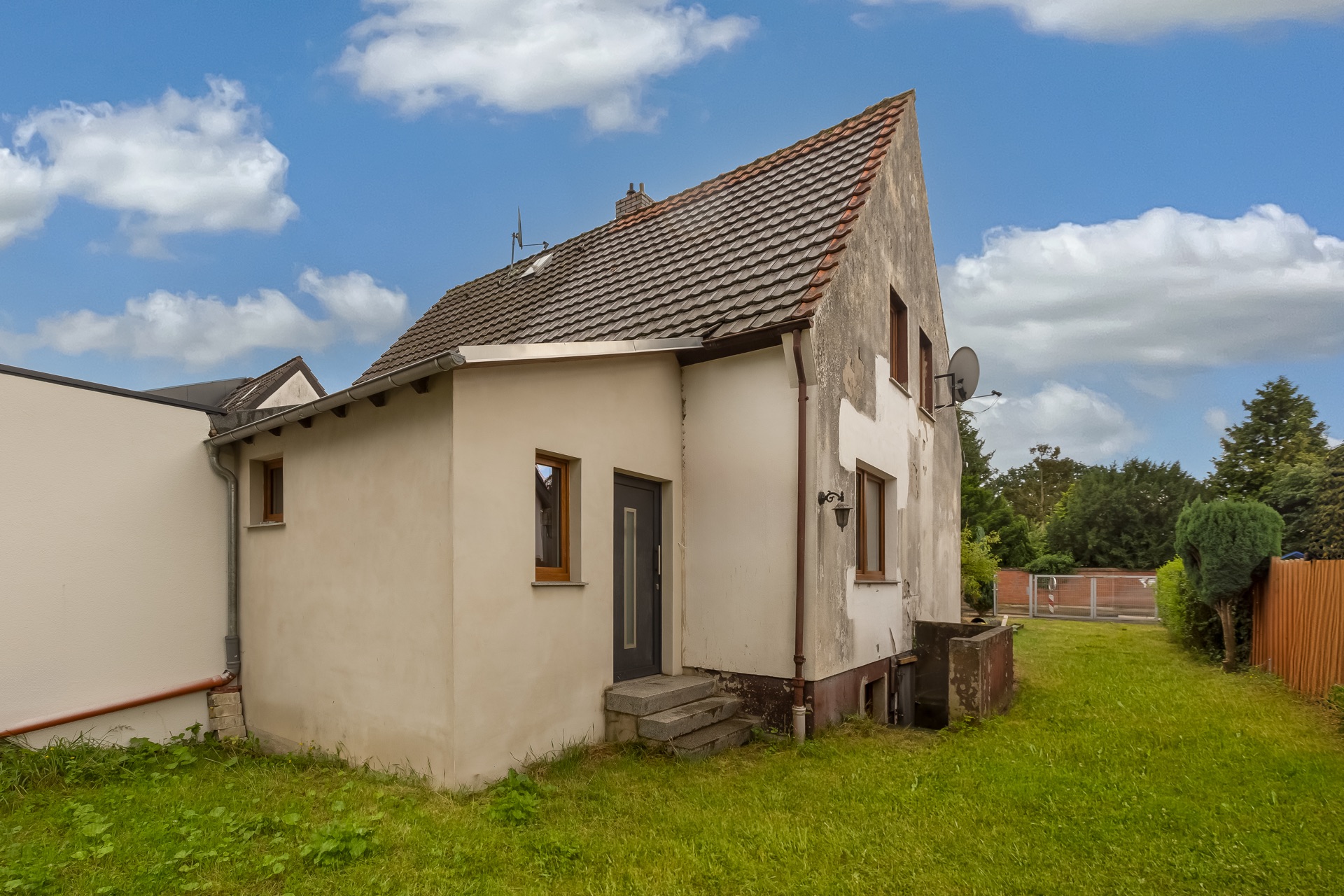 Zweistöckiges Wohnhaus mit Satteldach und Garten, teilweise verputzte Fassade.