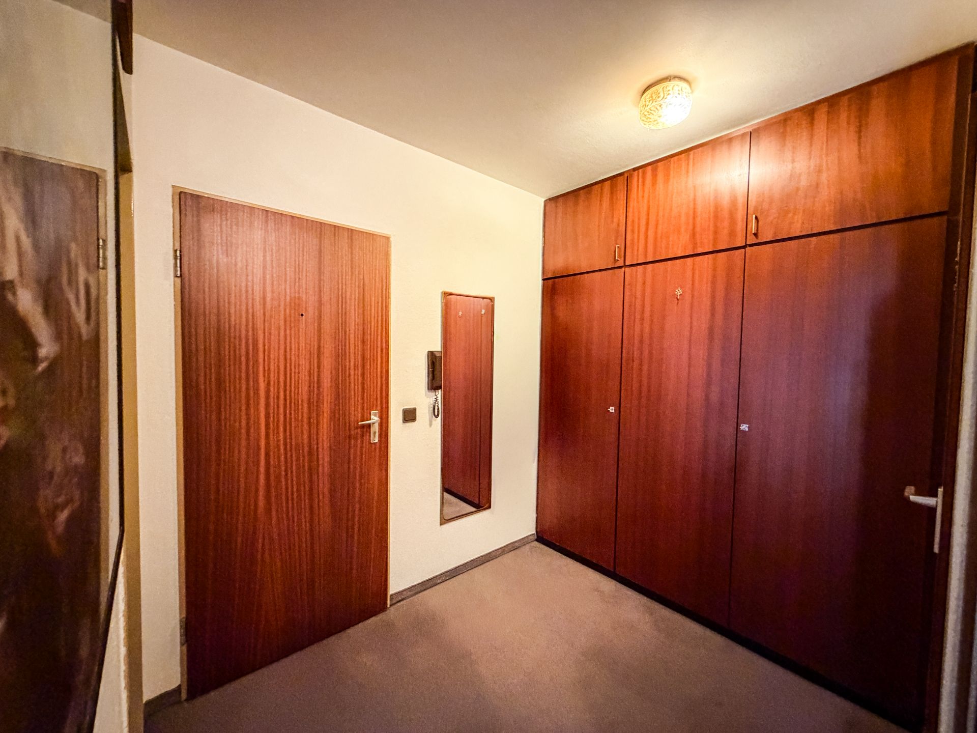 Flur mit Holztüren, großem Einbauschrank und Wandspiegel.