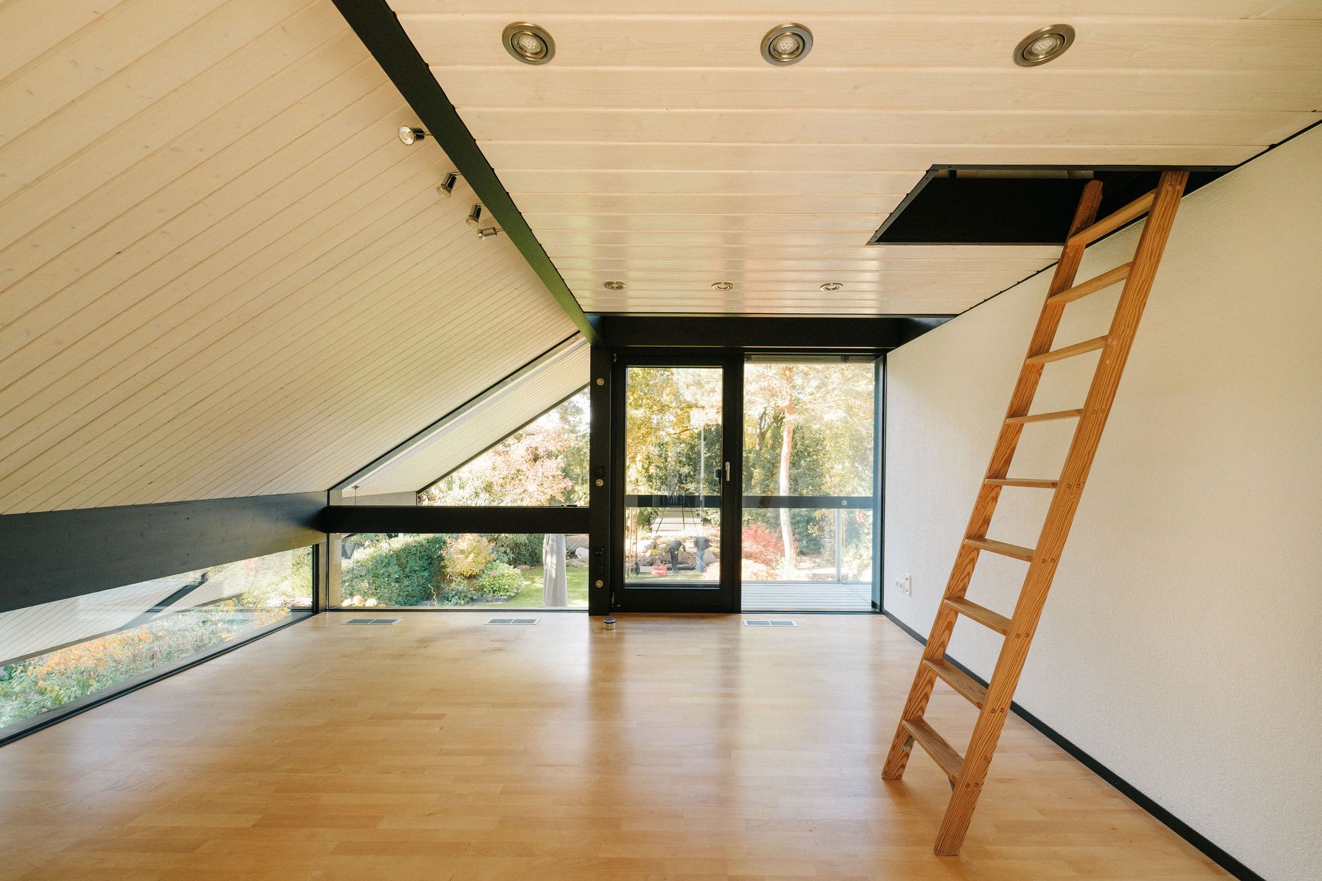 Heller Dachraum mit Holzleiter zur Decke, großen Fenstern und hellem Holzboden.