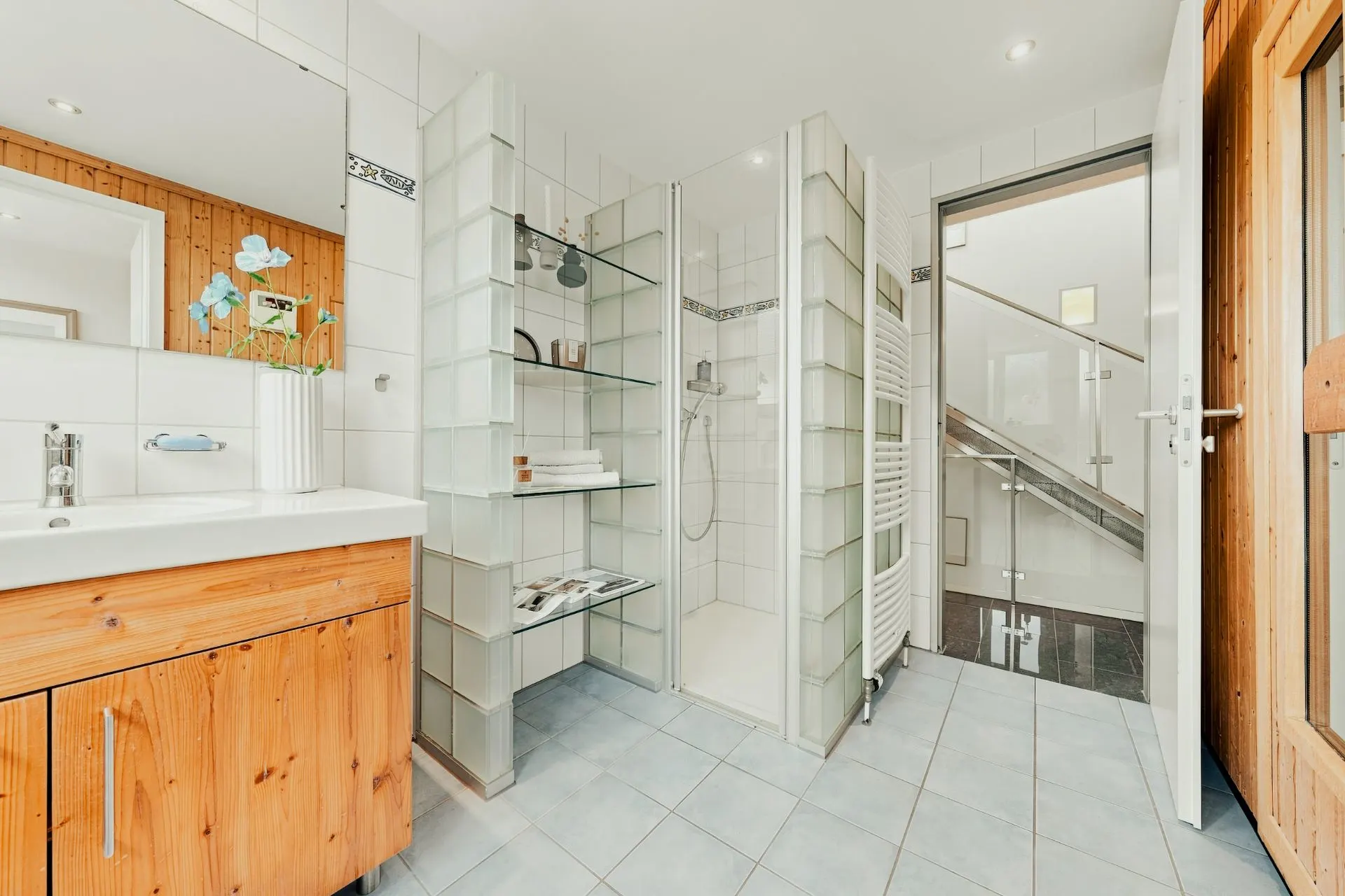 Modernes Badezimmer mit Holzmöbeln, offener Dusche und gefliestem Boden.