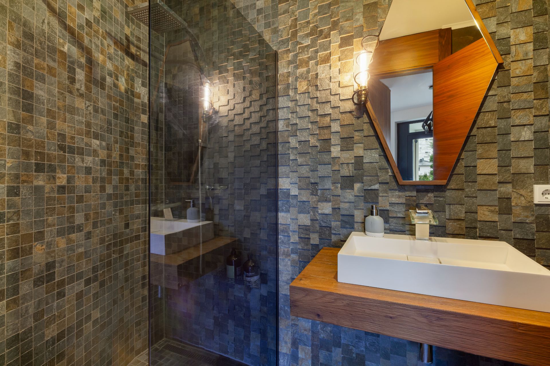Modernes Badezimmer mit eckigem Waschbecken, Holzablage, Spiegel und gefliester Wand.