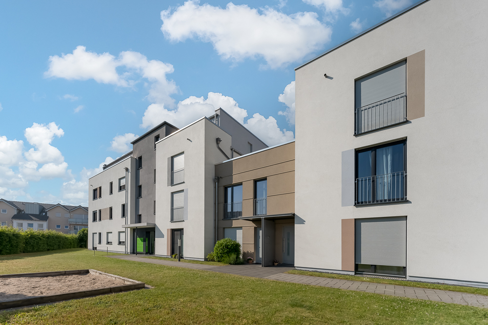 Modernes Wohnhaus mit mehreren Etagen, großem Garten und Sandkasten im Vordergrund.
