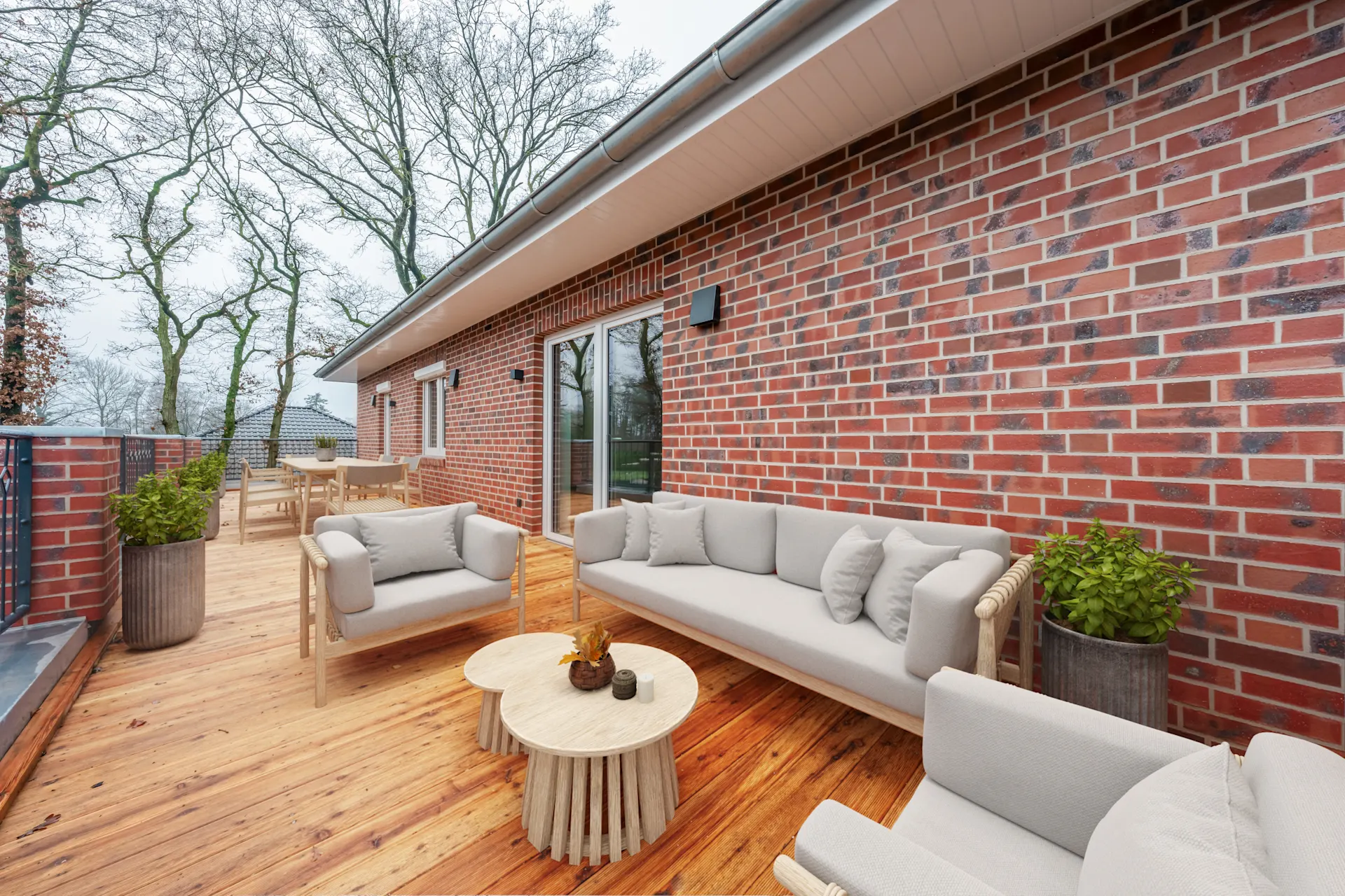 Große Holzterrasse mit Sitzmöbeln und Tischen an einem roten Backsteinhaus.