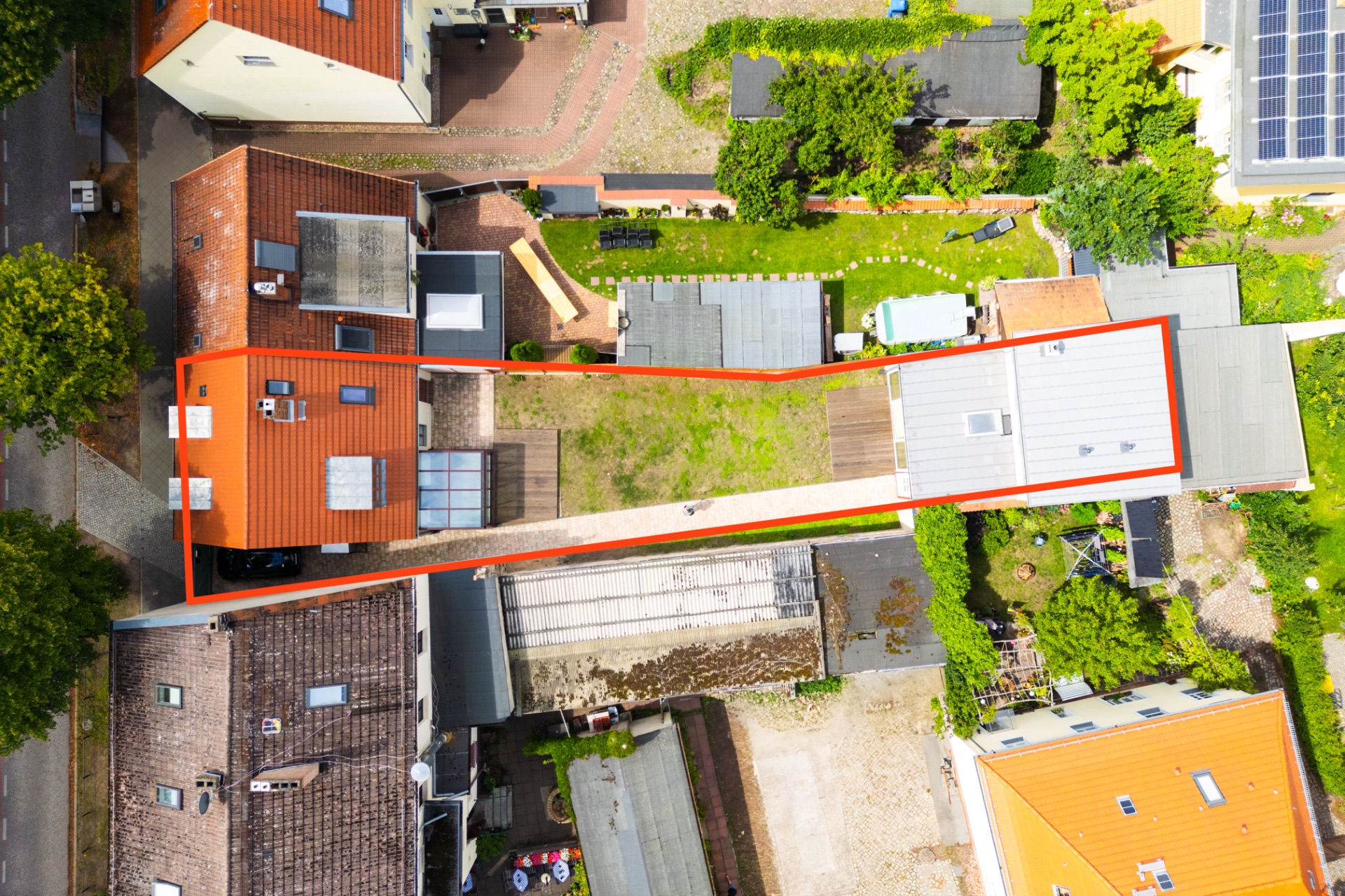 Luftaufnahme eines Grundstücks mit zwei Häusern und einem Garten, von roten Linien umrandet.