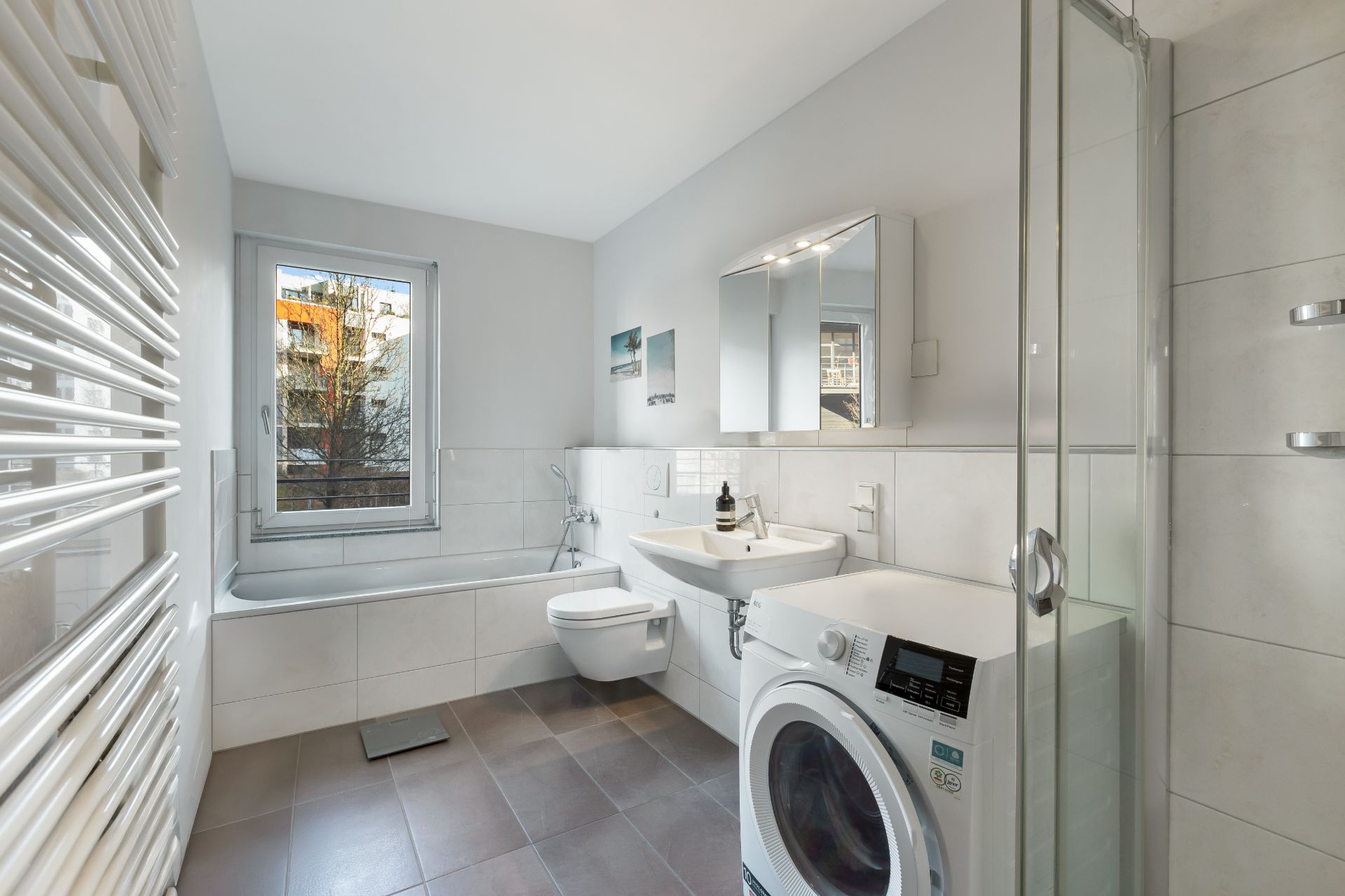 Modernes Badezimmer mit Badewanne, Dusche, Waschbecken, Waschmaschine und Fenster.