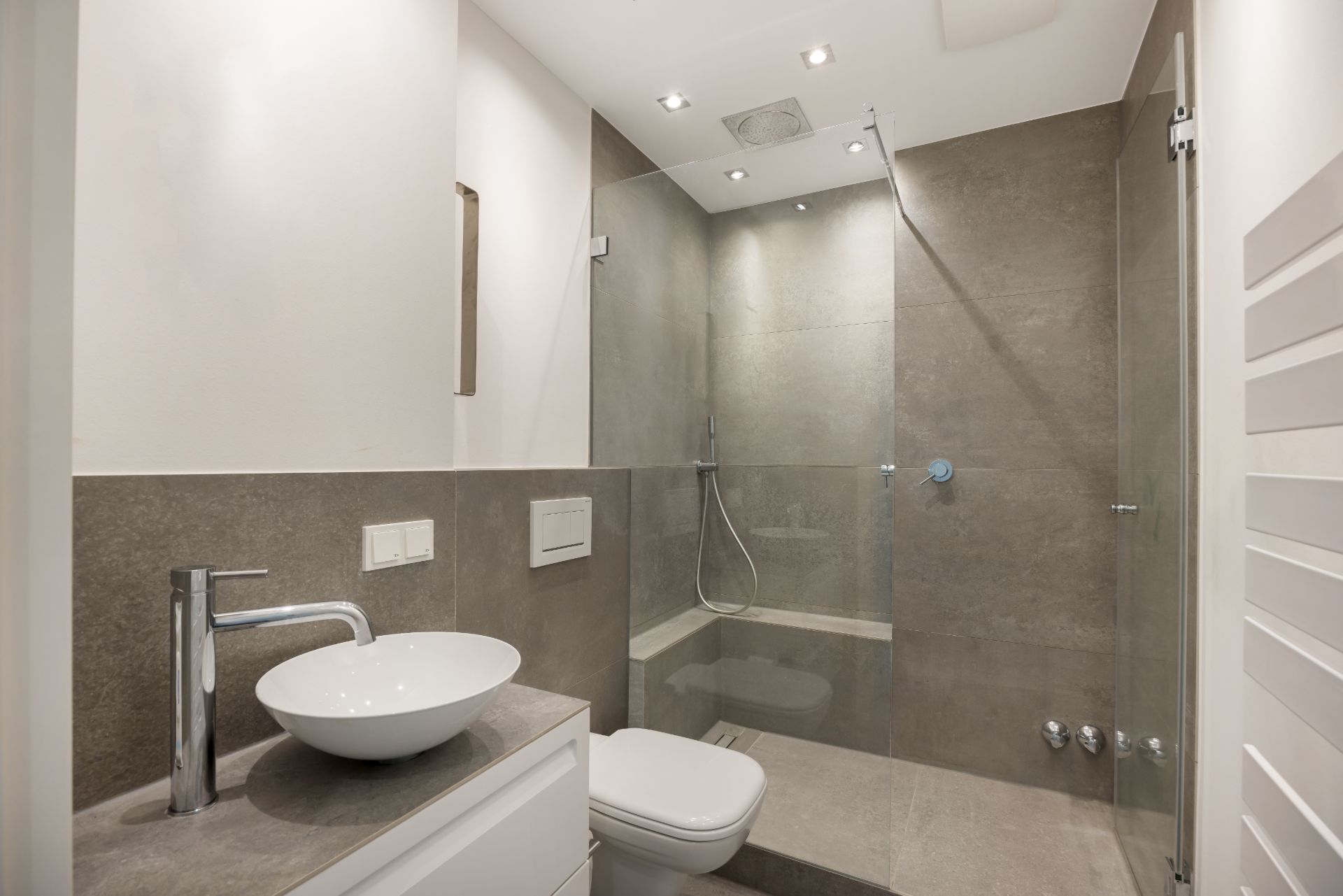 Modernes Badezimmer mit begehbarer Dusche, Waschbecken und WC.