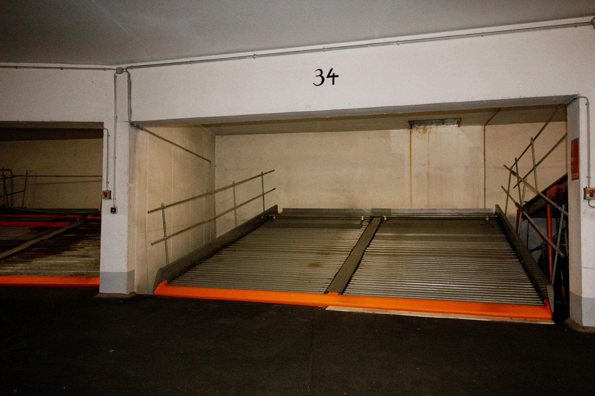Leerer, nummerierter Stellplatz in einer Tiefgarage mit Metallrampe und Geländer.