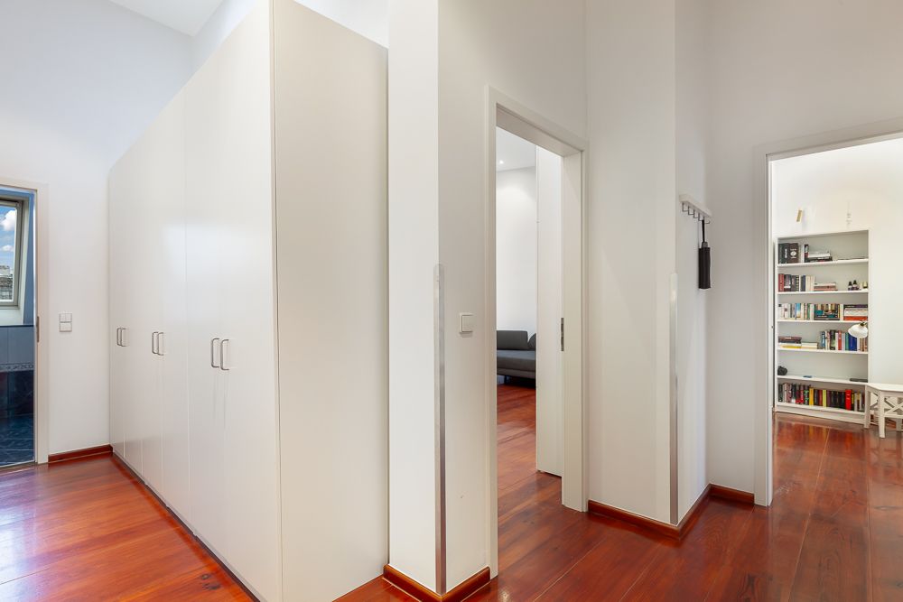 Flur mit weißem Einbauschrank, Holzboden und Zugang zu weiteren Zimmern.