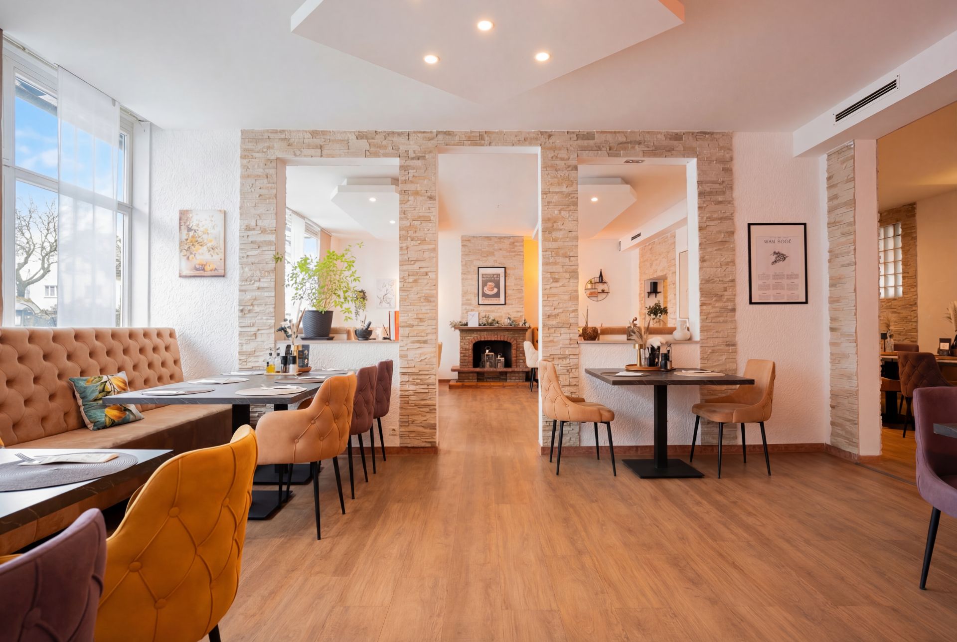 Geräumiges Wohnzimmer mit Holzboden, Esstischen, Polsterstühlen und großen Fenstern.