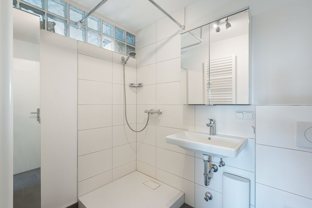 Modernes Badezimmer mit begehbarer Dusche, Waschbecken und Spiegel.