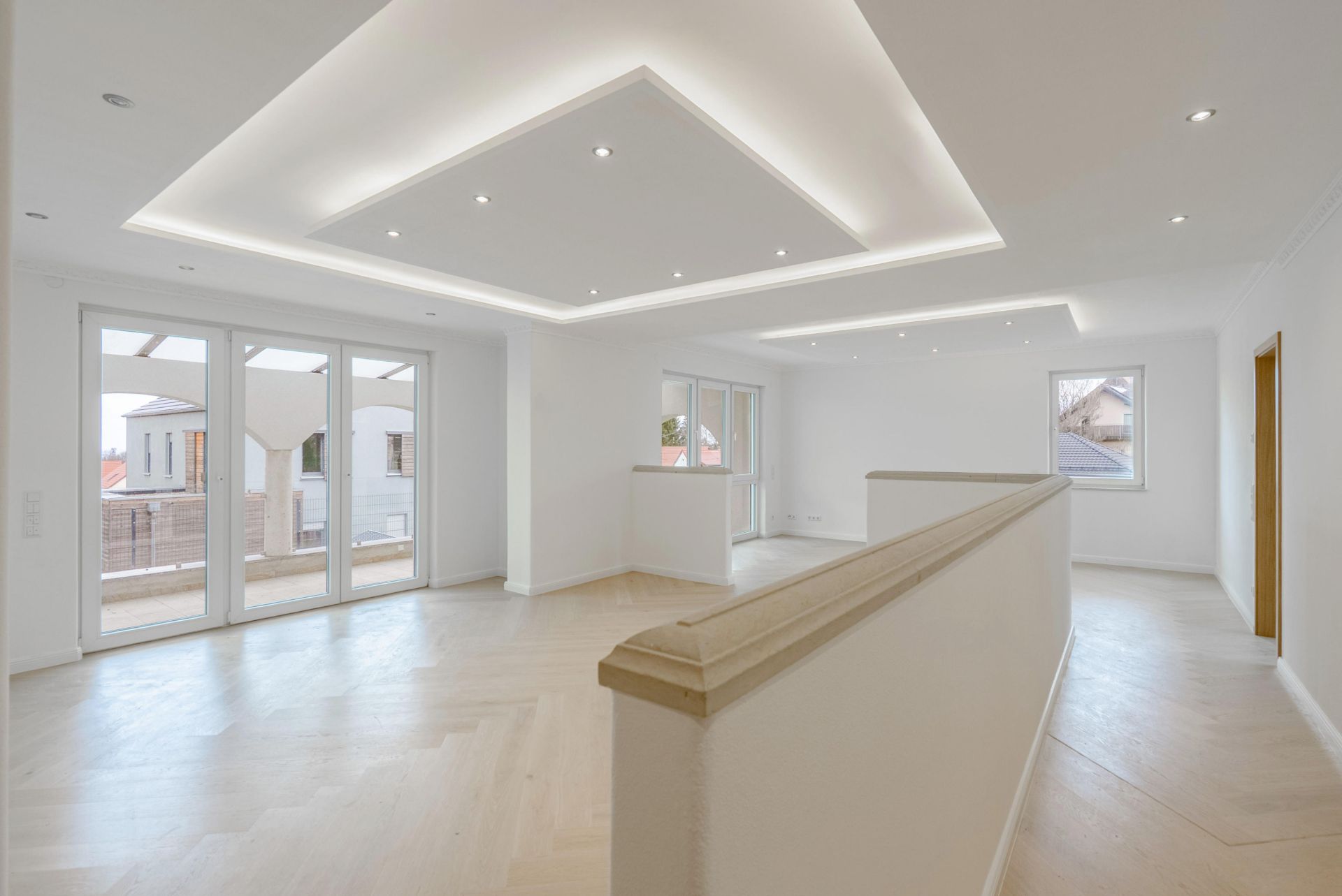 Helles, modernes Wohnzimmer mit großen Fenstern und Deckenbeleuchtung.