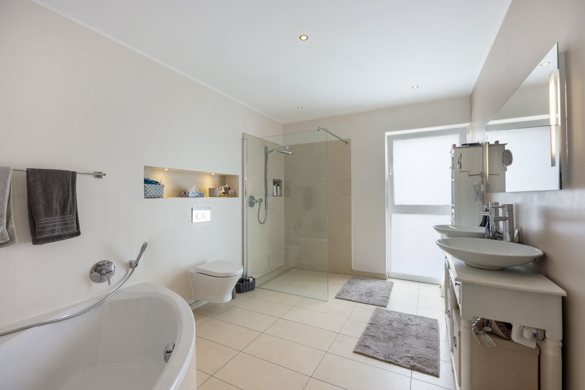 Modernes Badezimmer mit freistehender Badewanne, bodengleicher Dusche und Doppelwaschbecken.