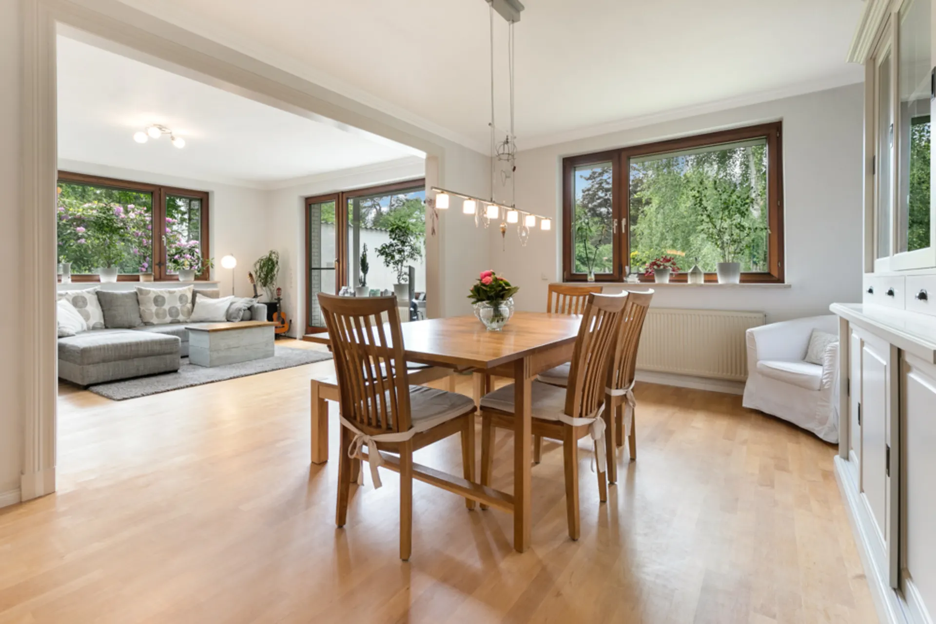 Heller Essbereich mit Holztisch und sechs Stühlen, angrenzend an Wohnzimmer mit Sofa.