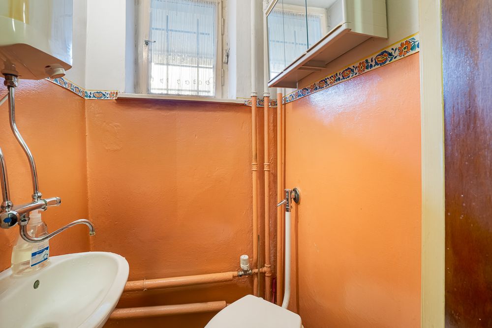 Kleines Badezimmer mit orange gestrichenen Wänden, Waschbecken und Toilette.