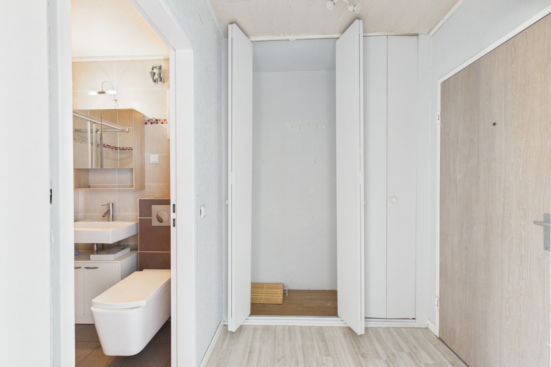 Flur mit offenem Einbauschrank und Blick in ein modernes Badezimmer.