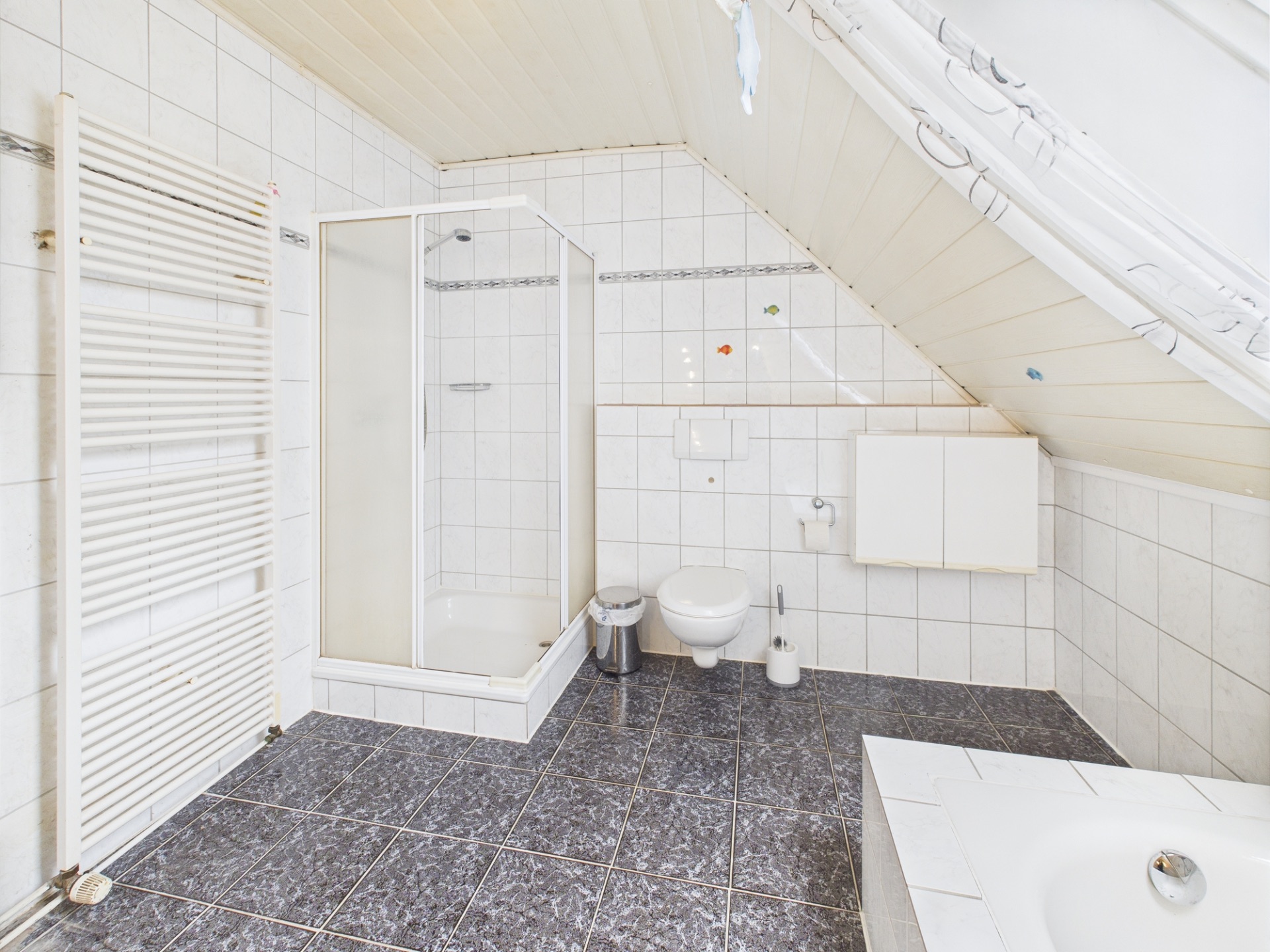 Helles Badezimmer mit Dusche, WC, Waschbecken und Schräge unter dem Dach.