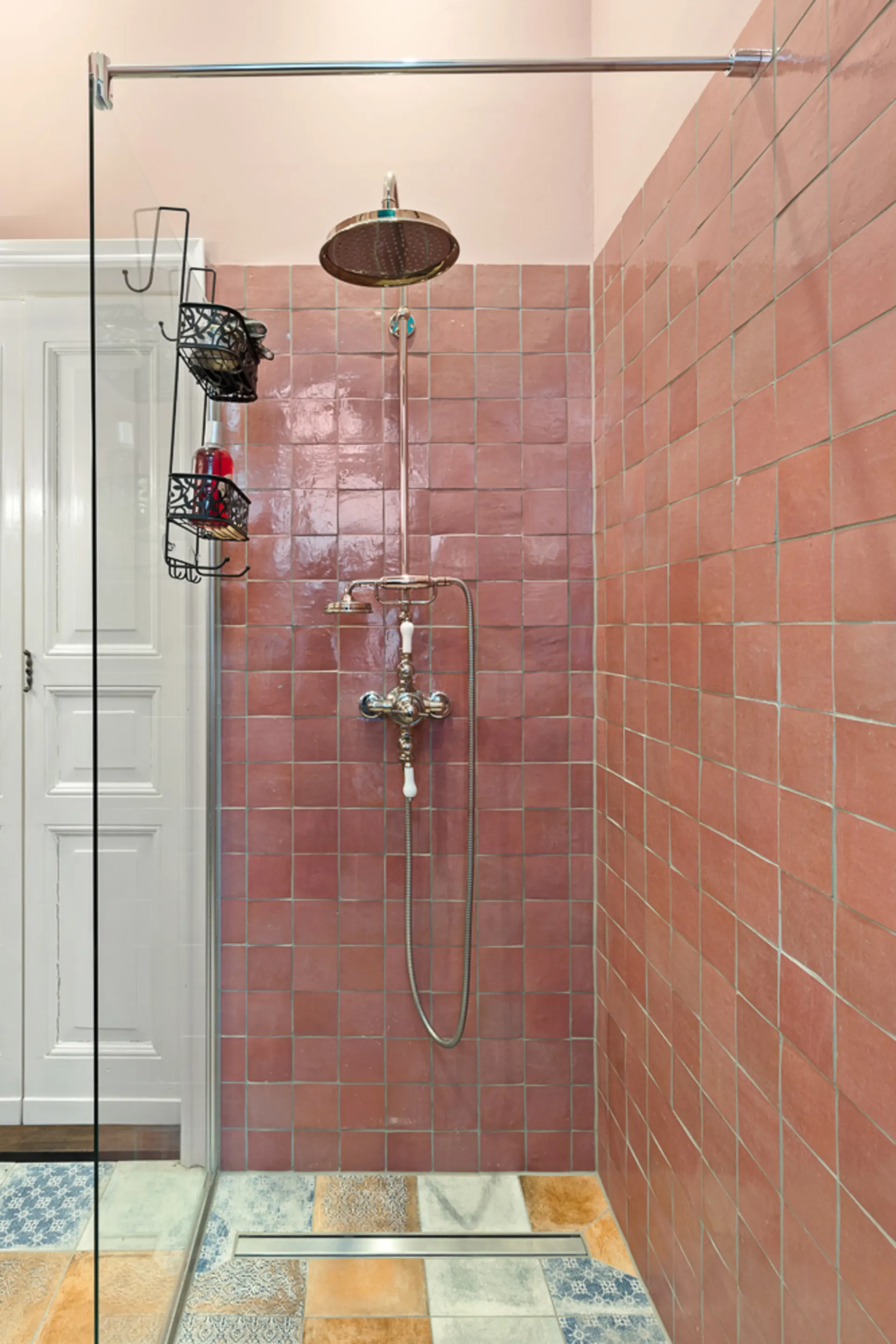 Dusche mit rosafarbenen Fliesen und Regendusche, bunter Fliesenboden.