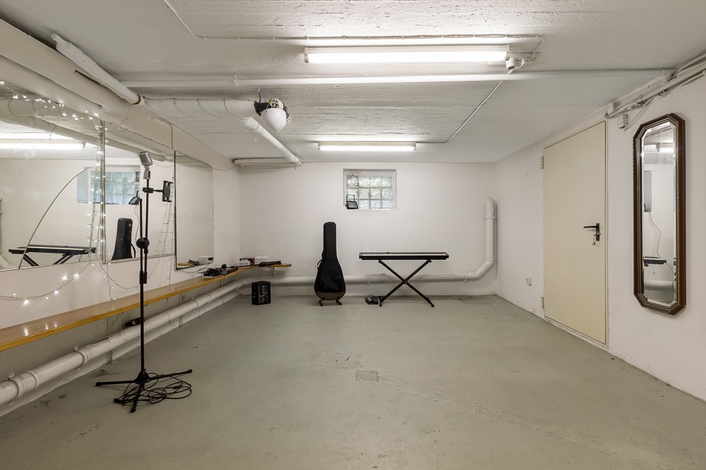 Kellerraum mit Spiegel, Ständer, Keyboard, Fenster und großem Wandspiegel.