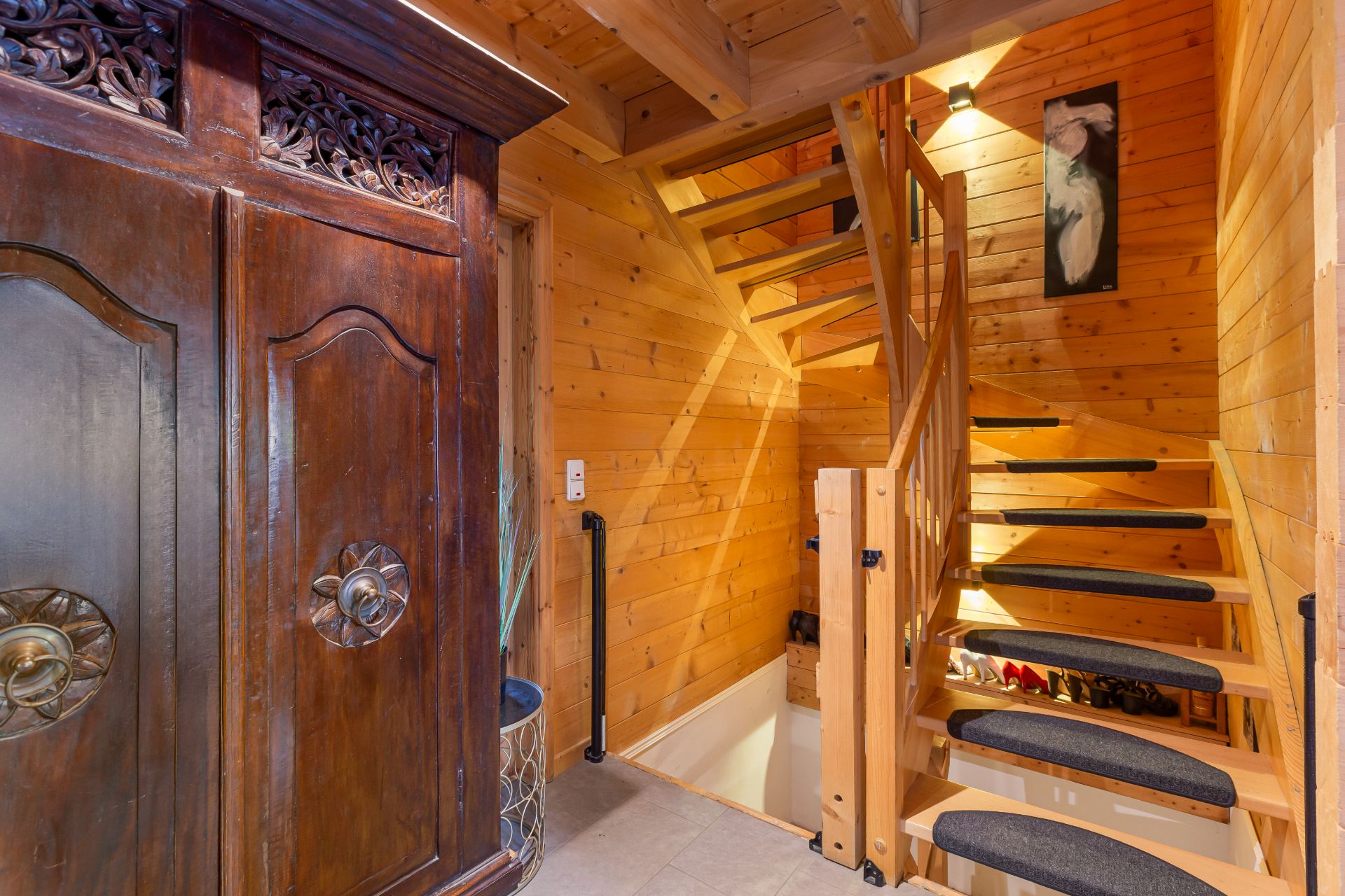 Holztreppe in einem Flur mit Holzverkleidung, großem Schrank und Wandbild.
