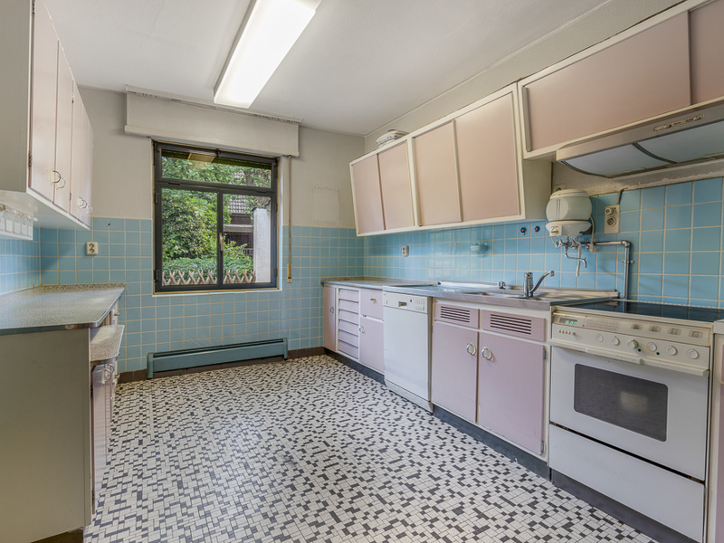 Helle Küche mit rosa Schränken, blau gefliesten Wänden und großem Fenster.