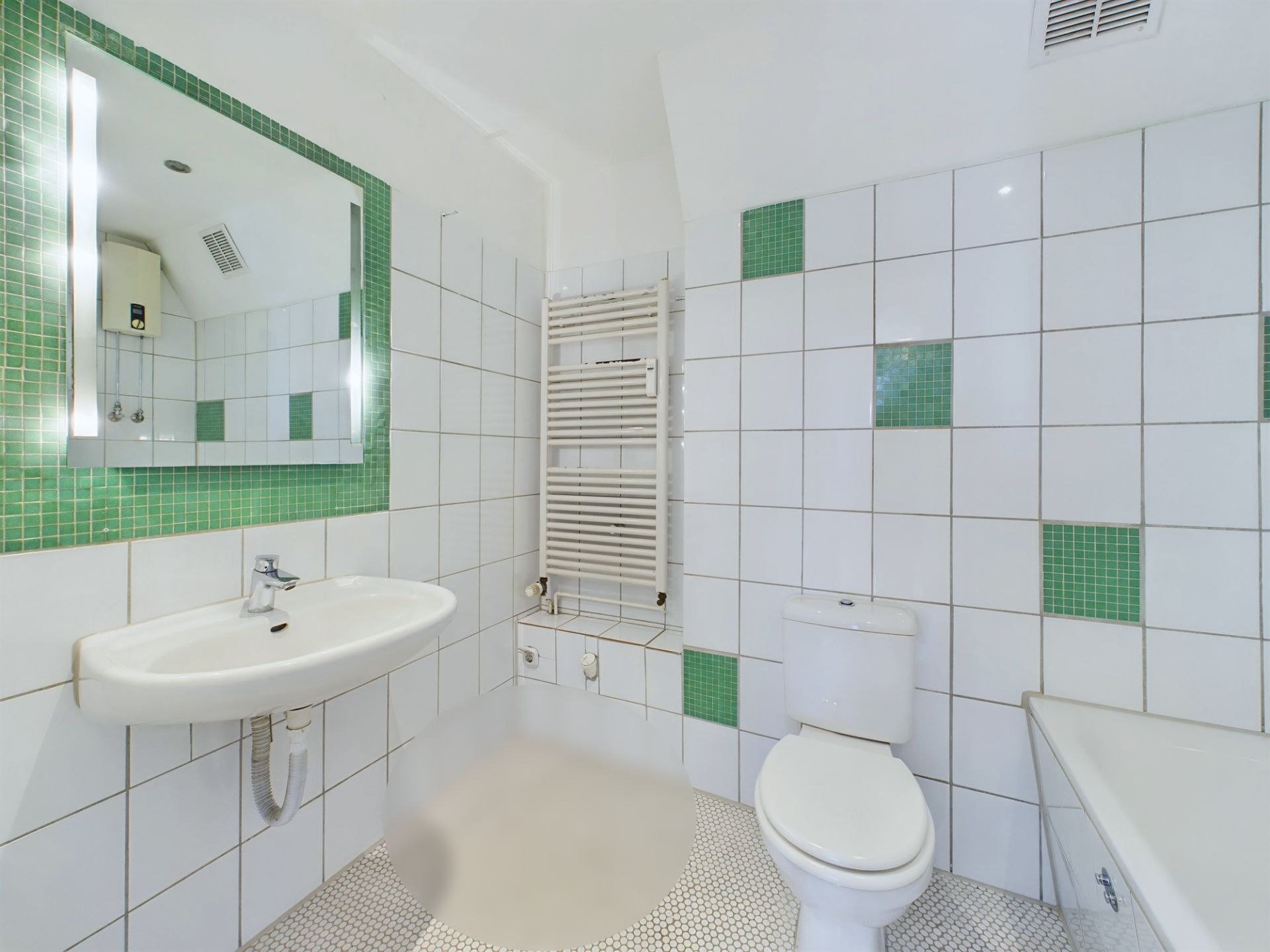 Modernes Badezimmer mit Waschbecken, Spiegel, WC, Badewanne und grünen Fliesenakzenten.