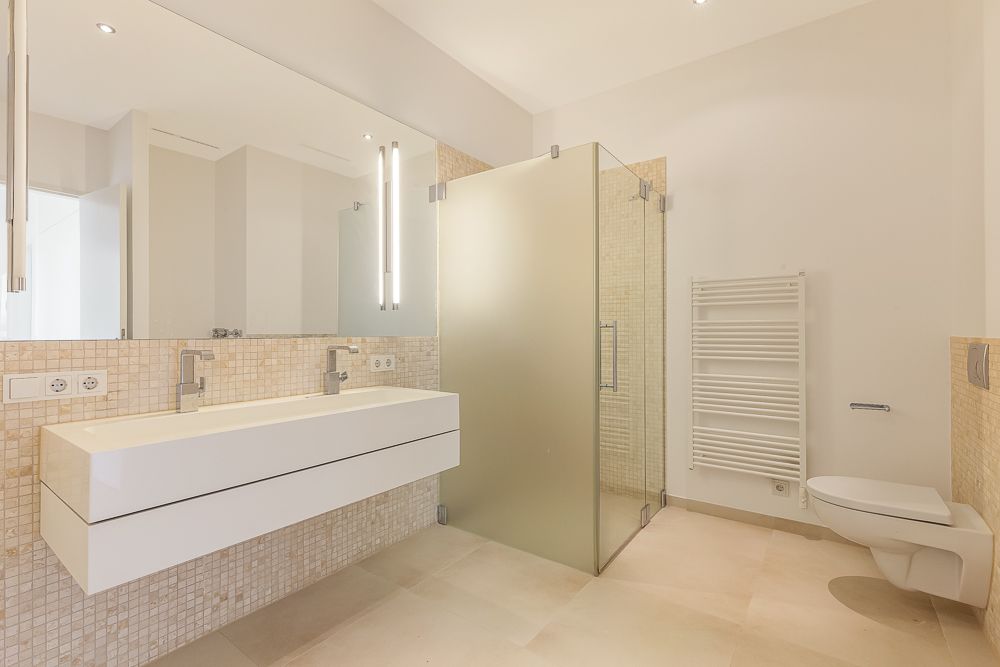 Modernes Bad mit Doppelwaschbecken, großer Spiegel, Dusche mit Glastür und Wand-WC.