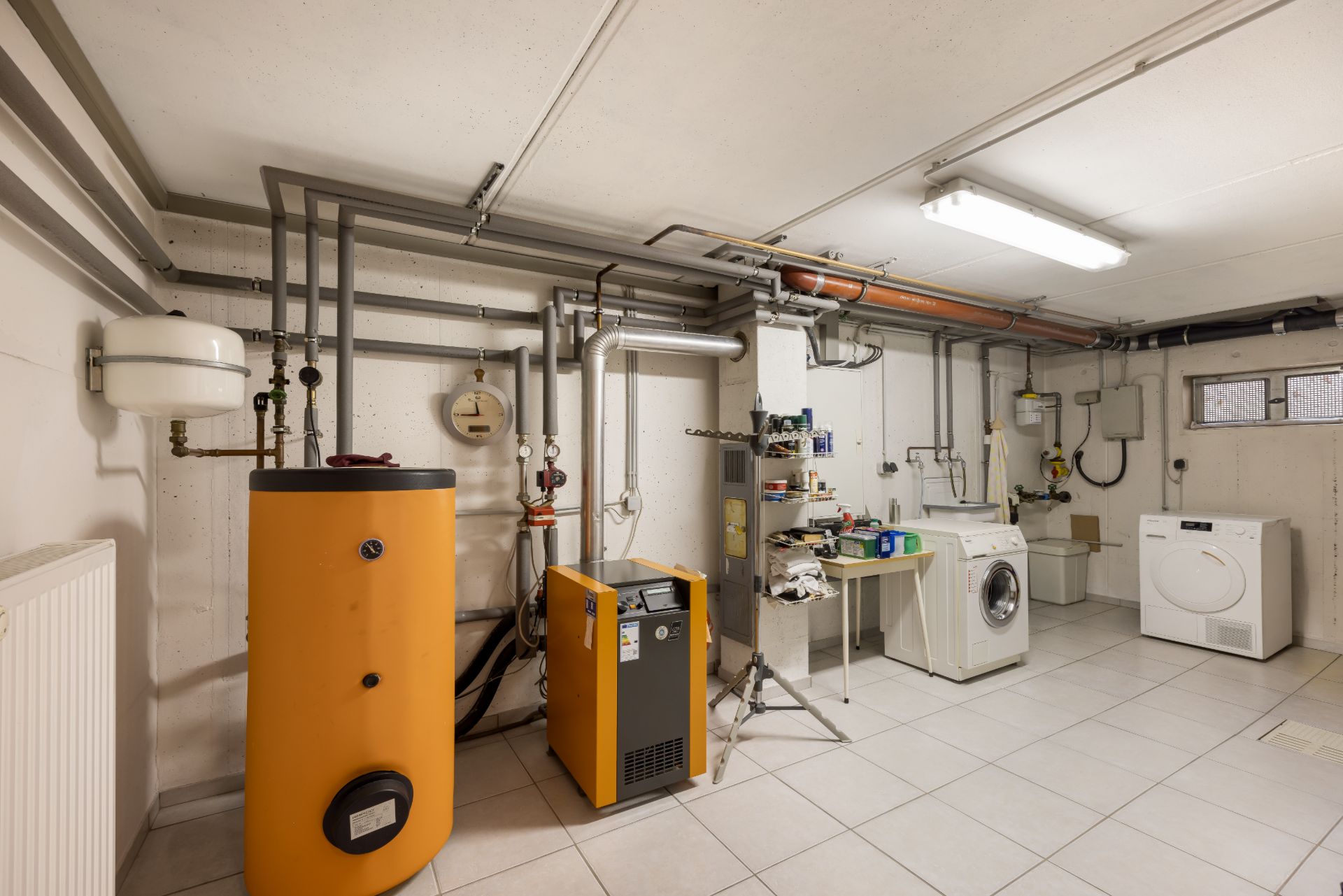 Hauswirtschaftsraum mit Heizungsanlage, Waschmaschine, Trockner und Werkbank.
