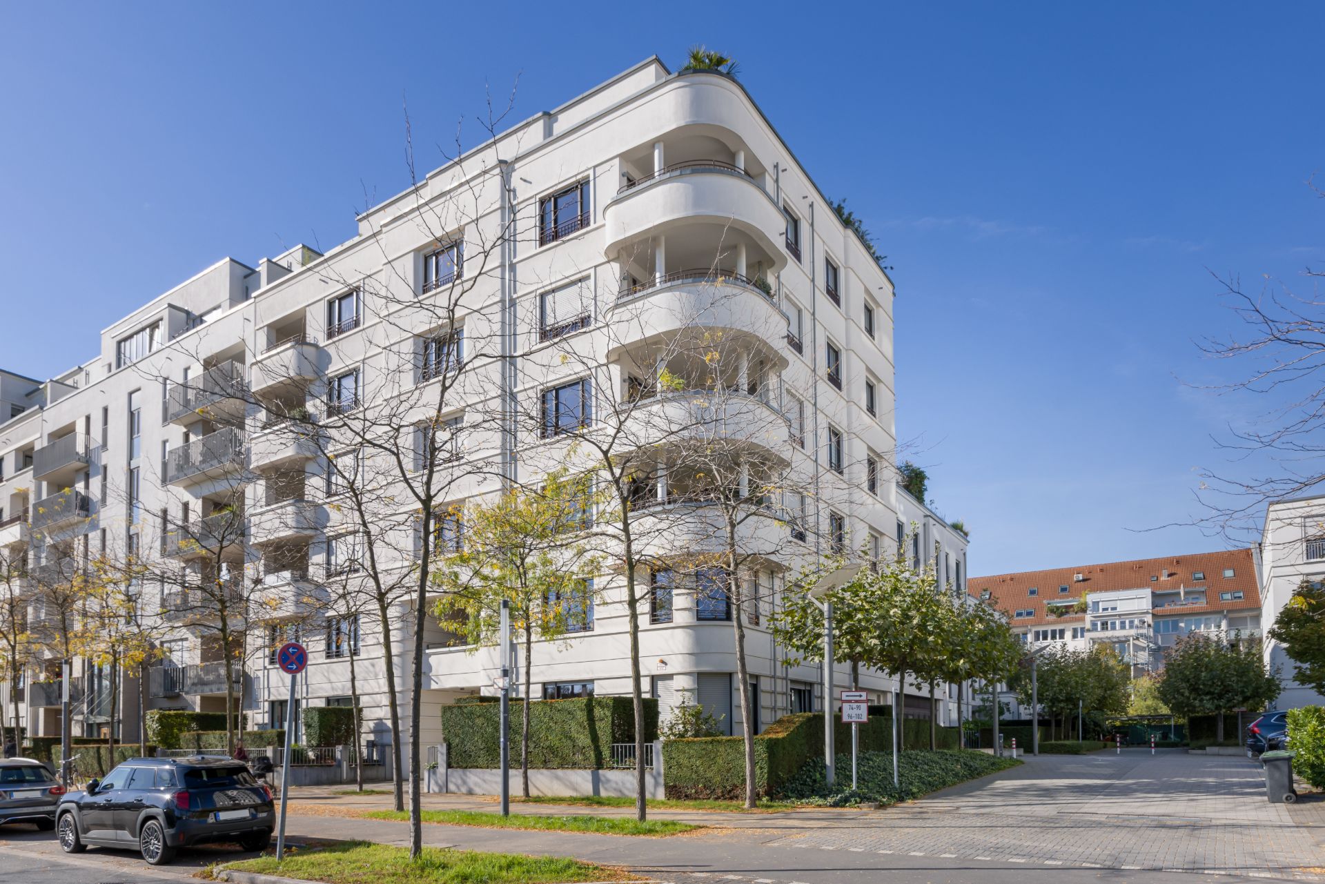Modernes Wohngebäude mit mehreren Balkonen und Bäumen an der Straße.
