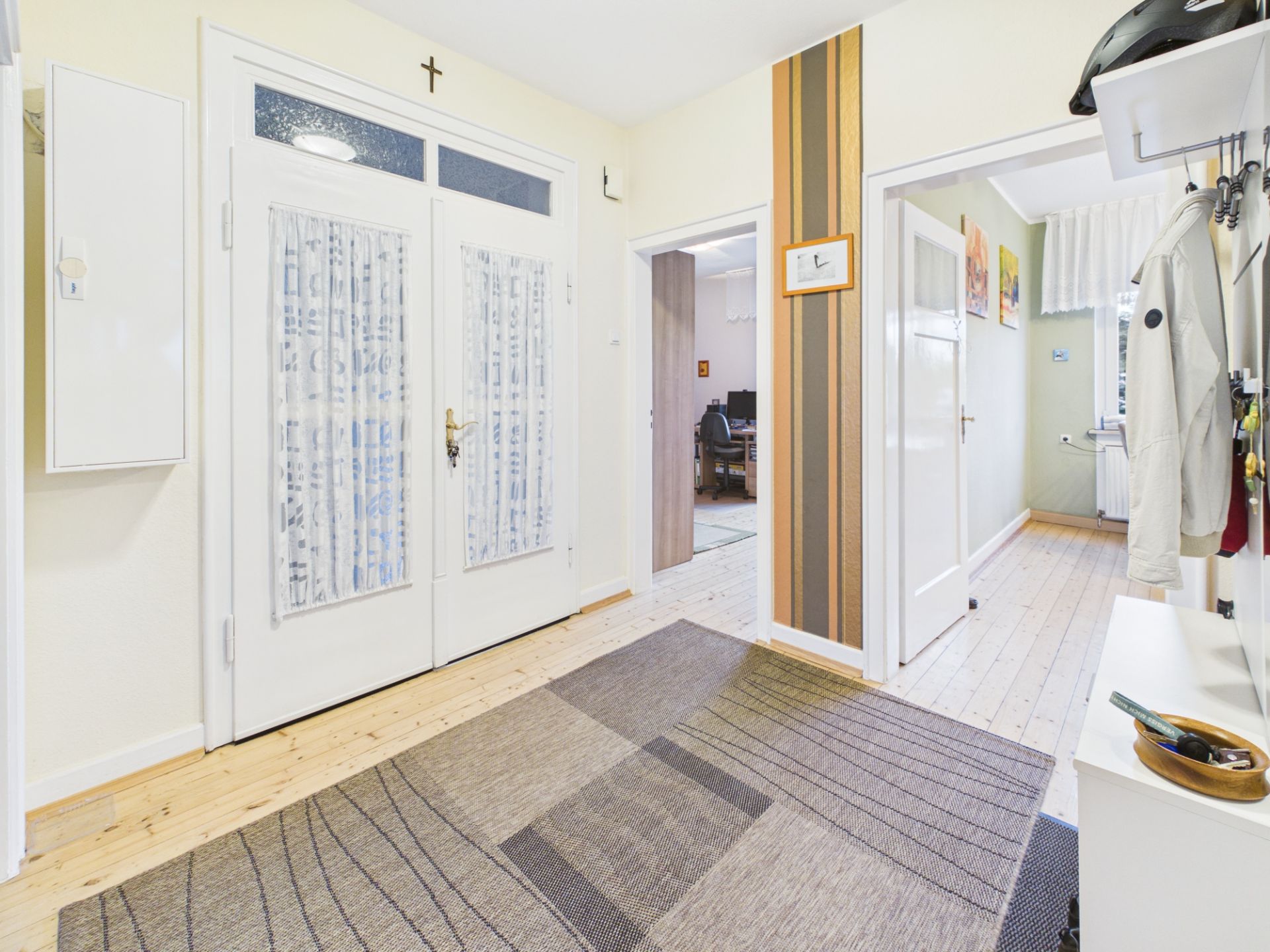 Heller Flur mit Teppich, Garderobe und mehreren Türen in einer Wohnung.