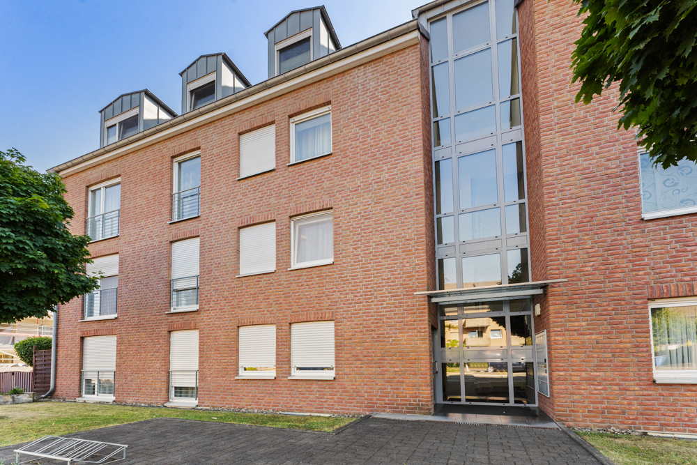 Mehrfamilienhaus mit roter Klinkerfassade und großem verglastem Eingangsbereich.