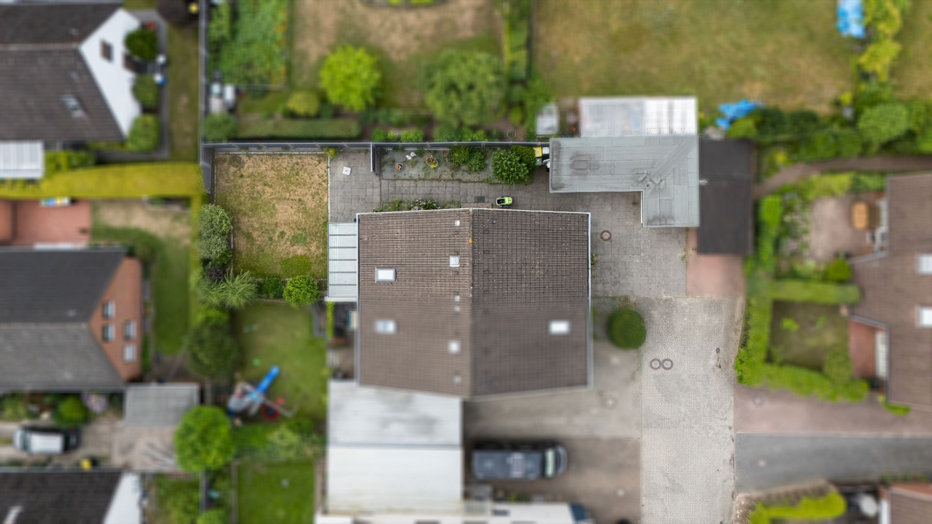 Luftaufnahme eines Wohnhauses mit Garten, Terrasse und Einfahrt, von oben fotografiert.