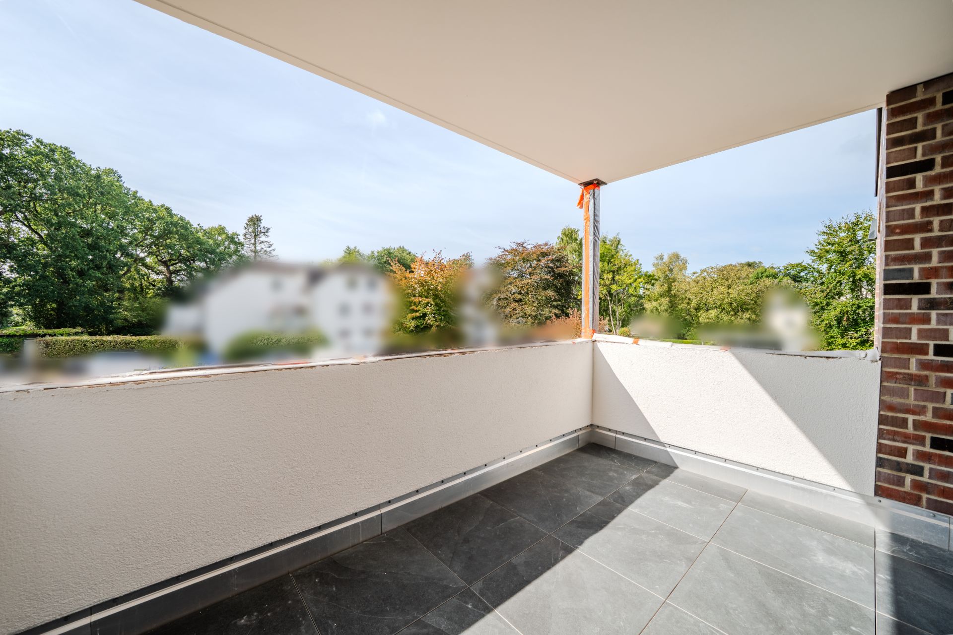Großer Balkon mit Fliesenboden und Blick ins Grüne.