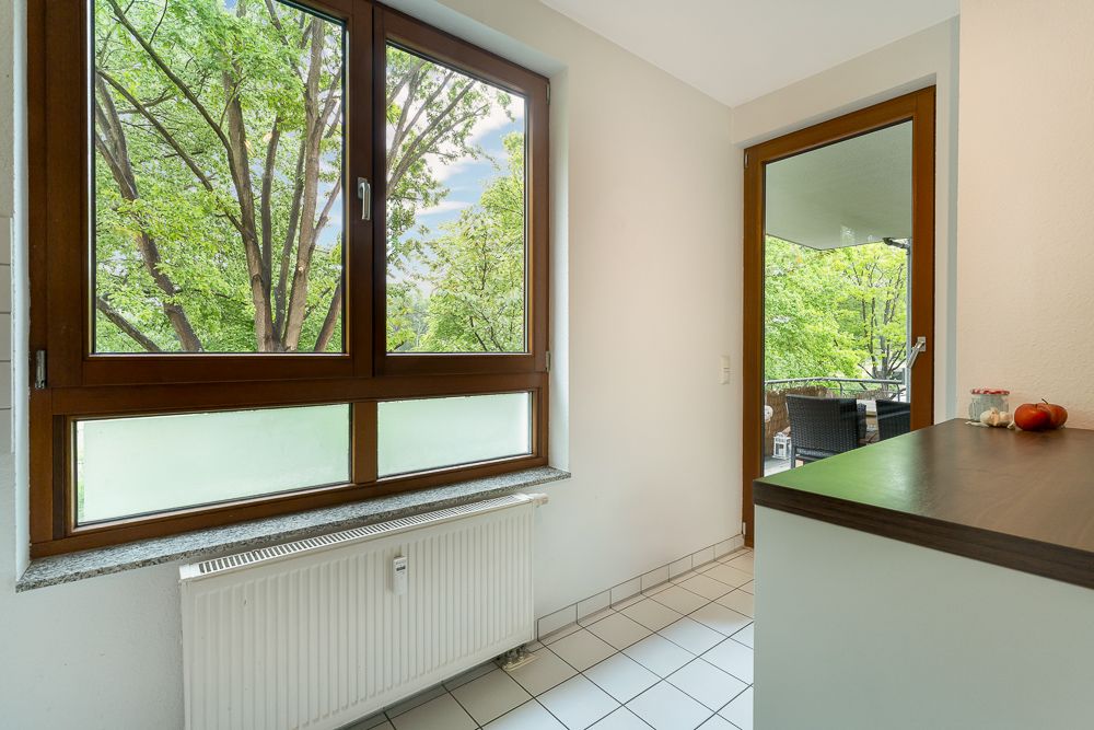 Heller Raum mit großem Fenster, Tür zum Balkon, Fliesenboden und Heizkörper.