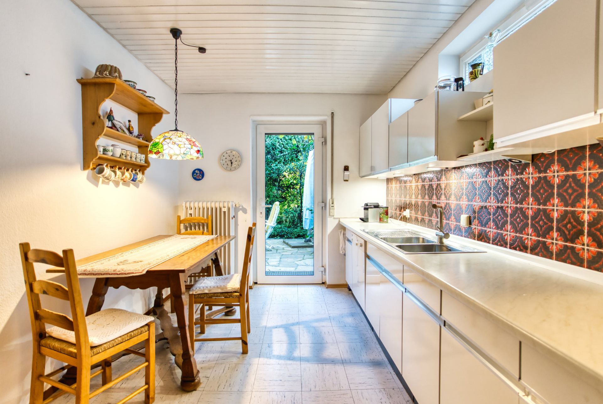 Helle Küche mit Esstisch, Holzstühlen und Tür zum Garten.