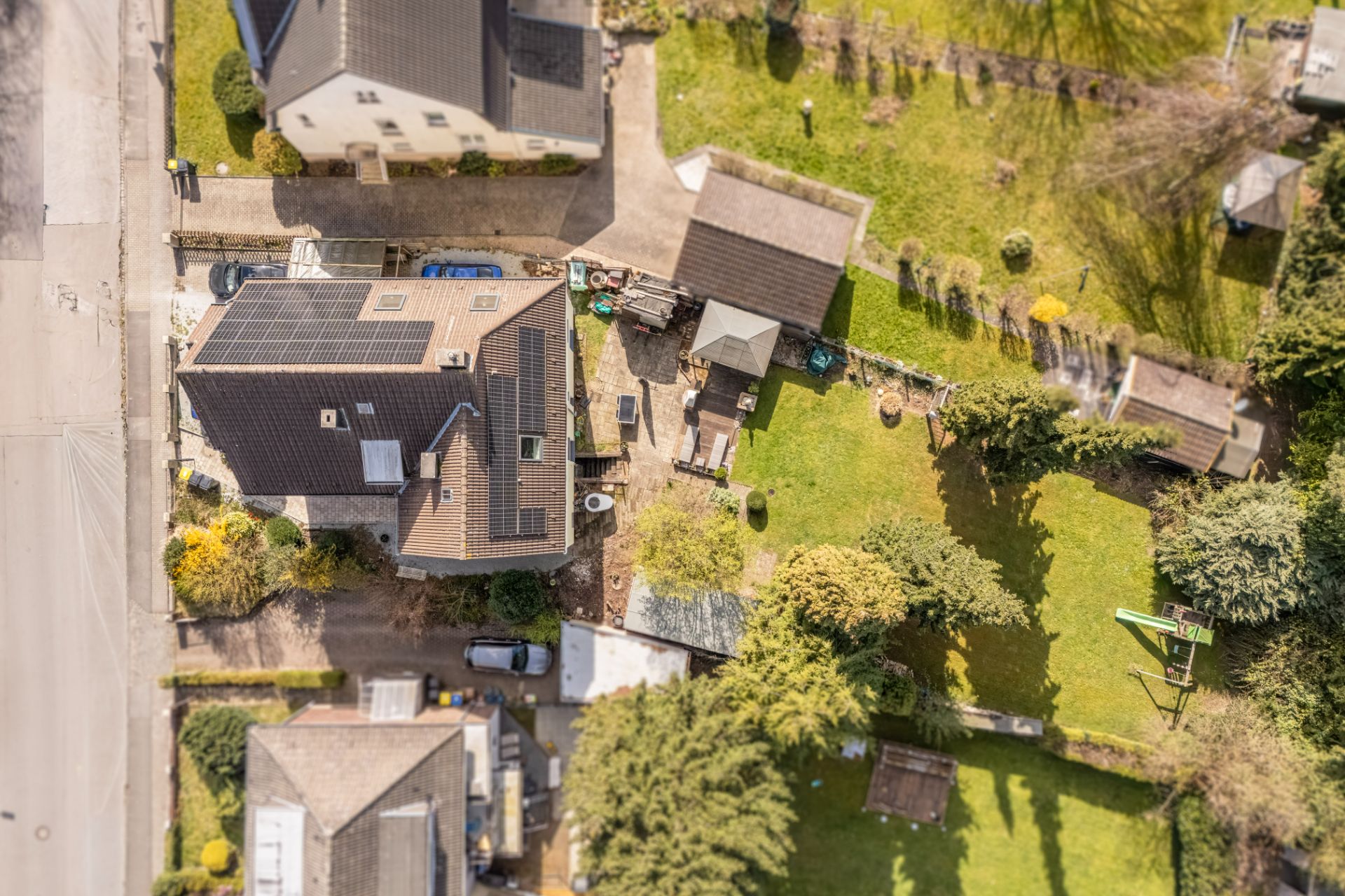 Luftaufnahme von einem Wohnhaus mit Garten, Nebengebäuden und umliegendem Grünbereich.