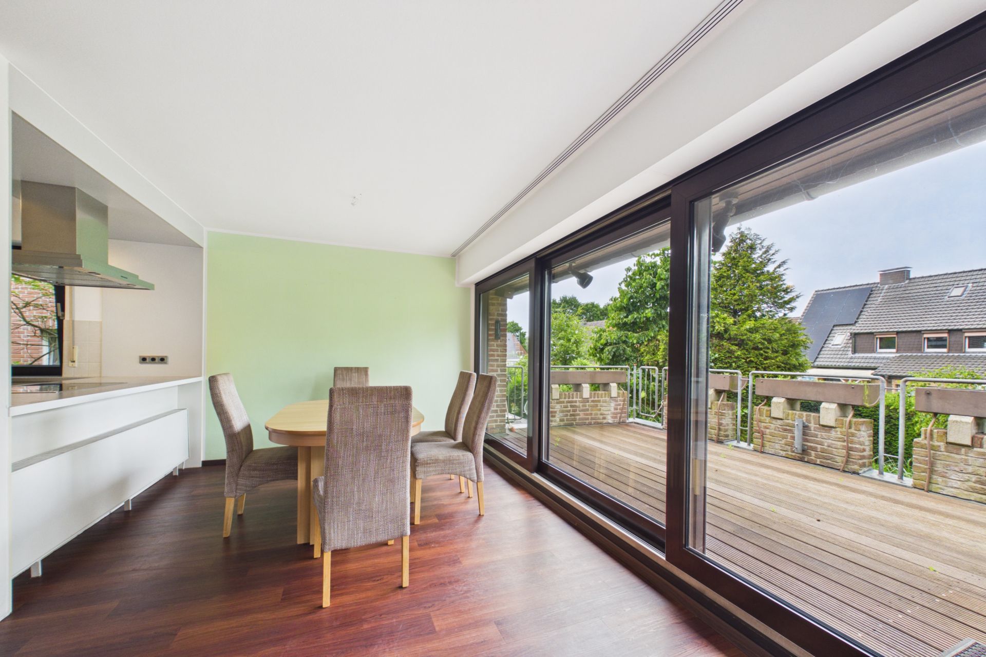 Essbereich mit rundem Tisch und Stühlen neben großen Fenstern mit Blick auf eine Terrasse.