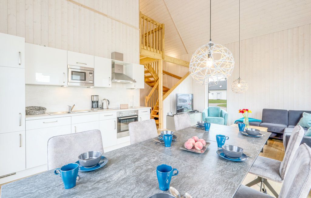 Helle Wohnküche mit Esstisch, moderner Küche, Sitzbereich und Holztreppe.