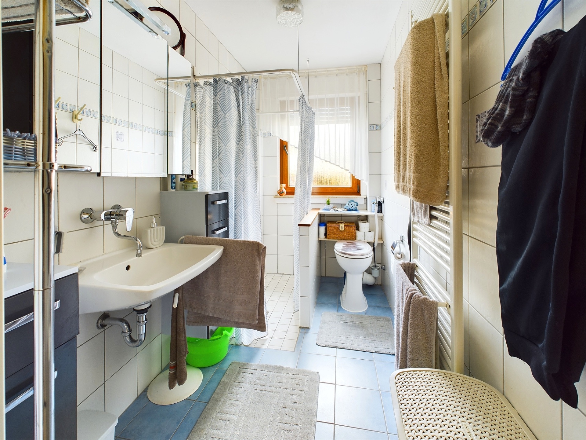Badezimmer mit Waschbecken, Dusche, Toilette, Handtüchern und Fenster.