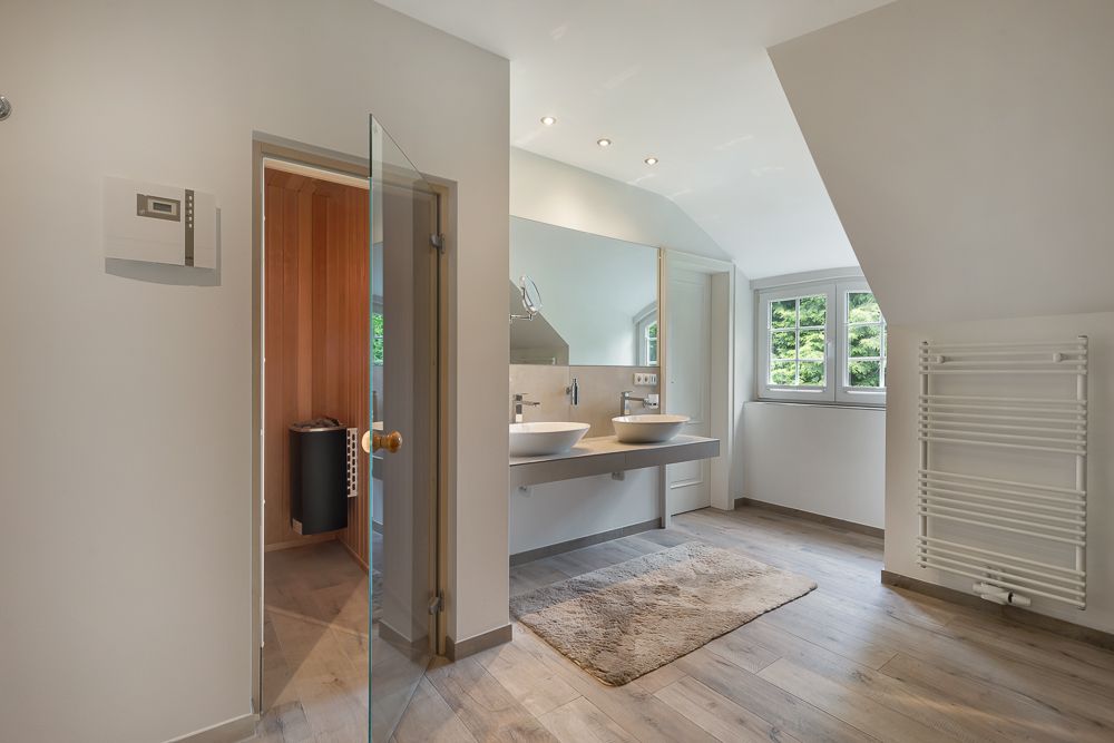 Modernes Badezimmer mit Doppelwaschbecken, großem Spiegel, Fenster und Handtuchheizkörper.