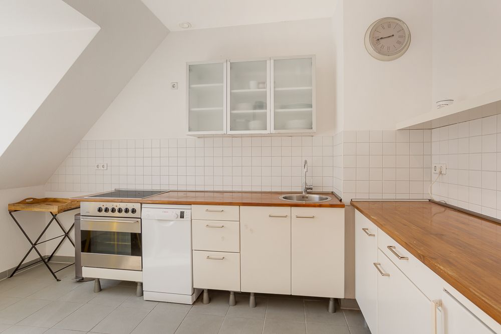 Helle Küche mit Holzarbeitsplatten, Herd, Spüle, Geschirrspüler und Hängeschränken.