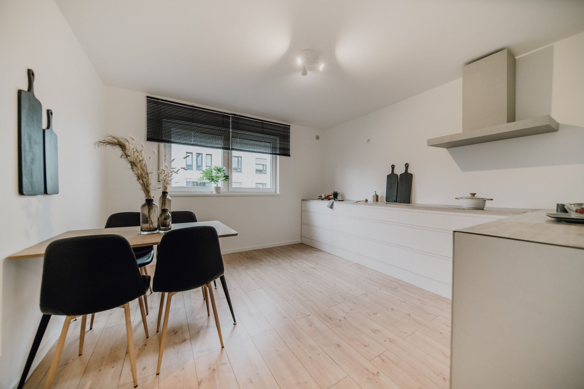 Helle, moderne Küche mit Esstisch, vier Stühlen und großen Fenstern.