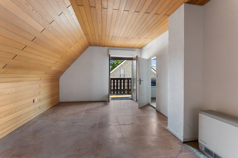 Leeres Zimmer mit Holzwänden und -decke, Tür führt auf einen Balkon.